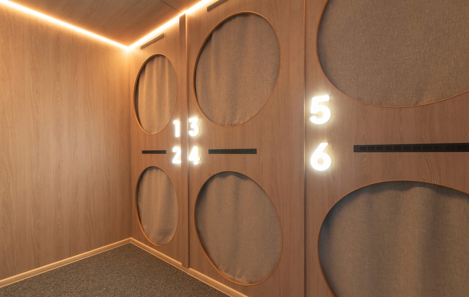 Modern capsule hotel room with circular sleeping pods, numbered for each guest.