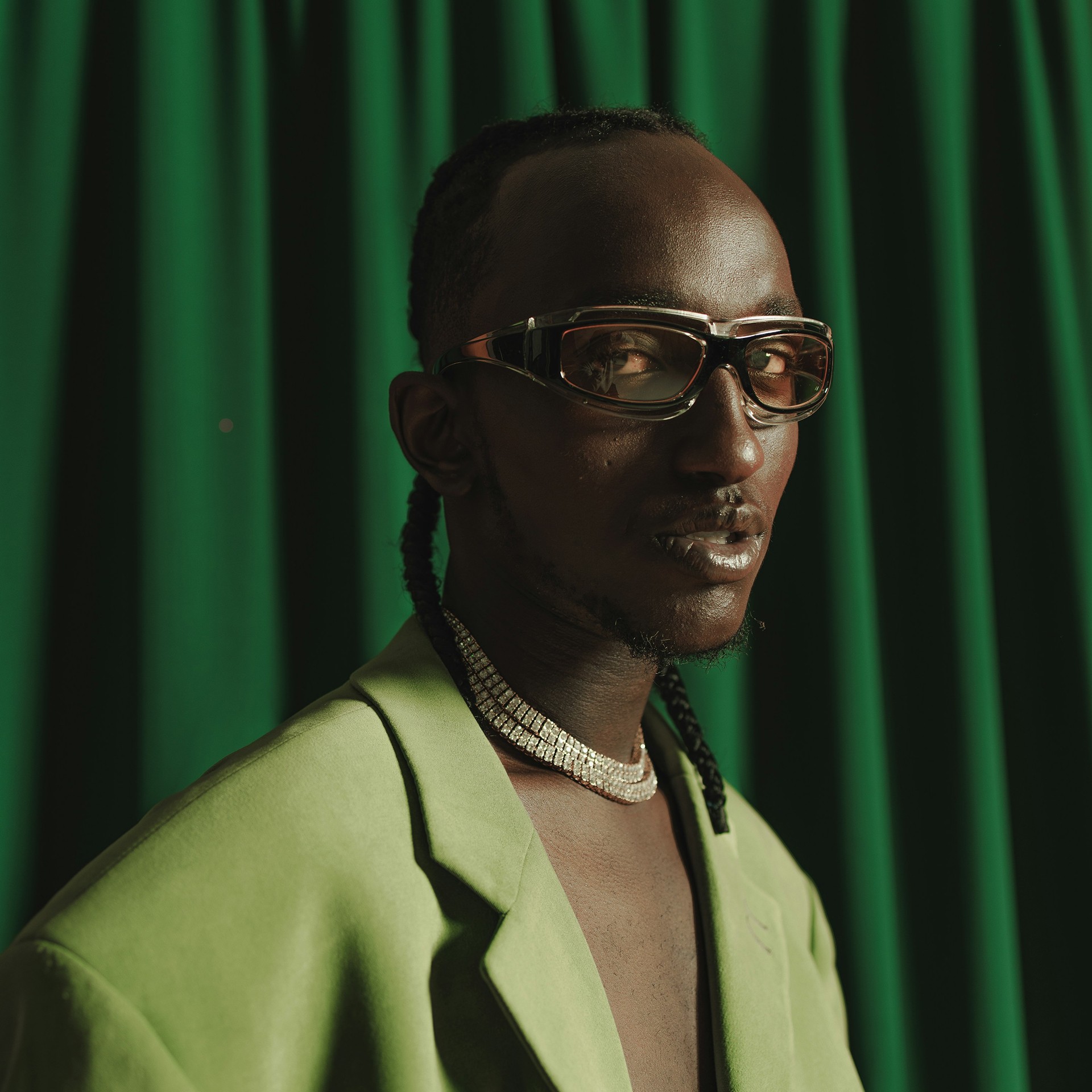 A man poses in front of a green curtain