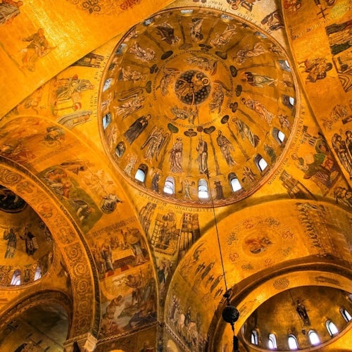 Techo ornamentado con cúpula dorada, decorado con intrincados frescos e iconografía religiosa, iluminado por luz natural.