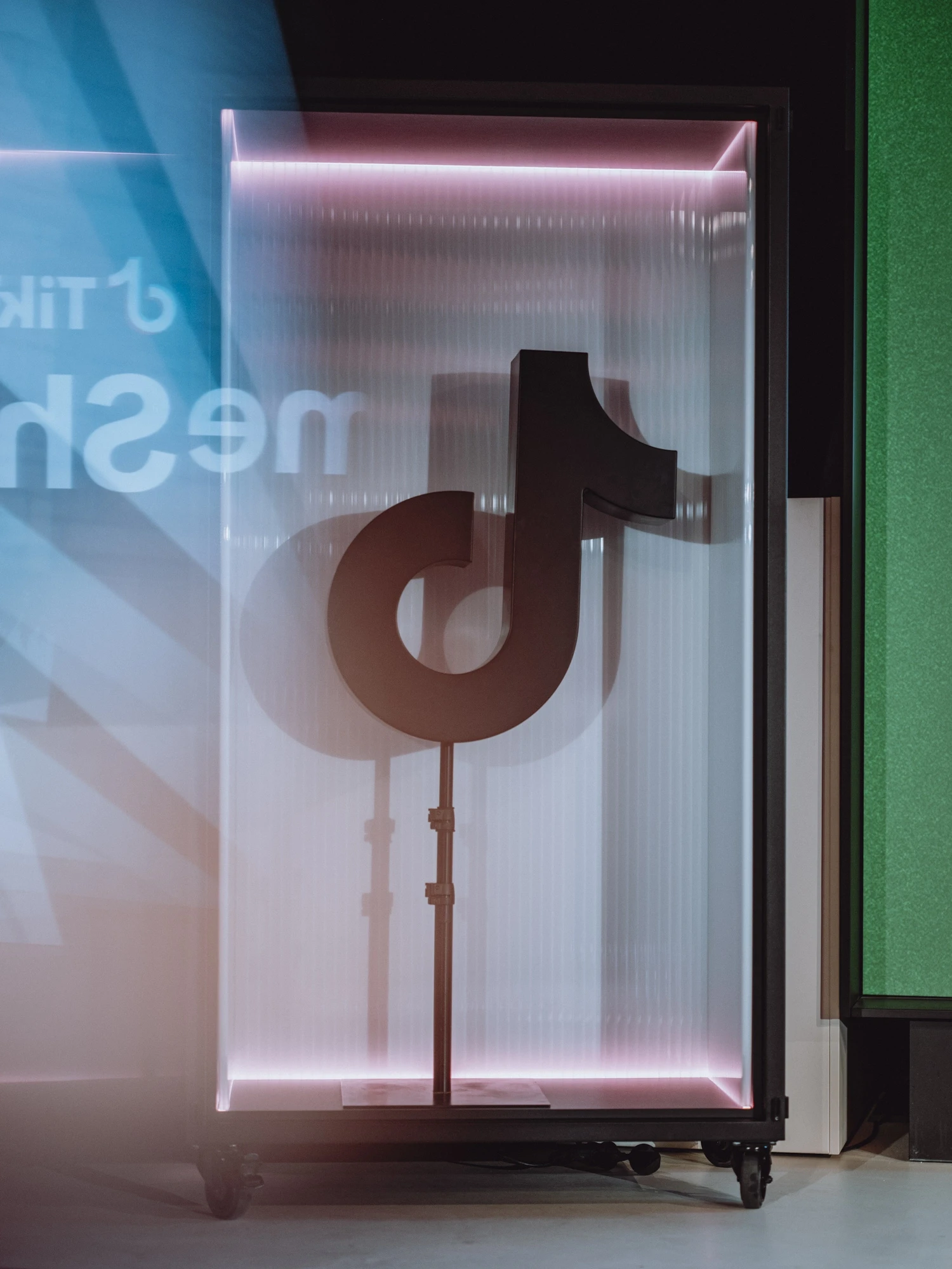 Black TikTok logo sculpture in a glass case with pink light edges on the stage.