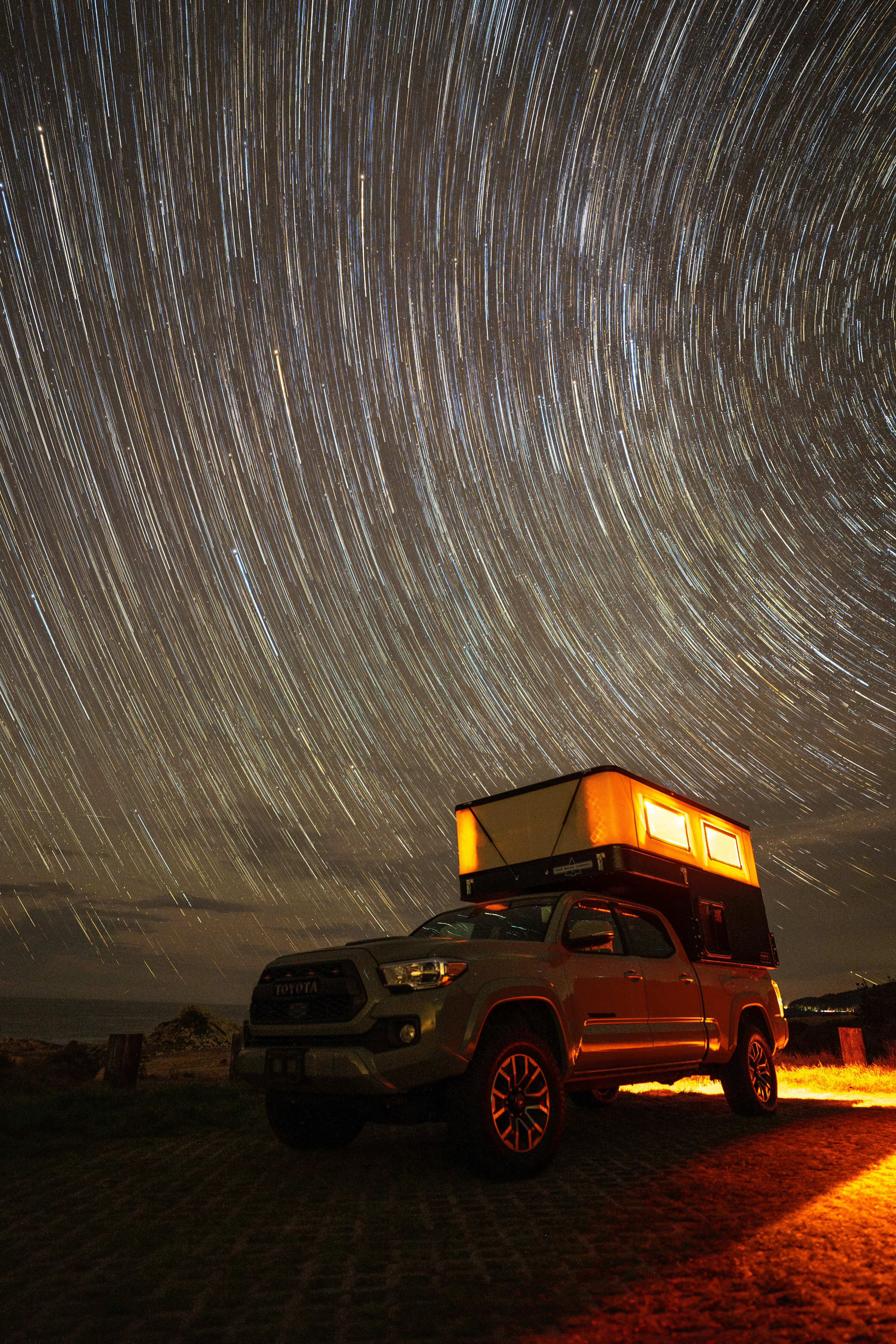 Truck with rooftop tent under star trails at night