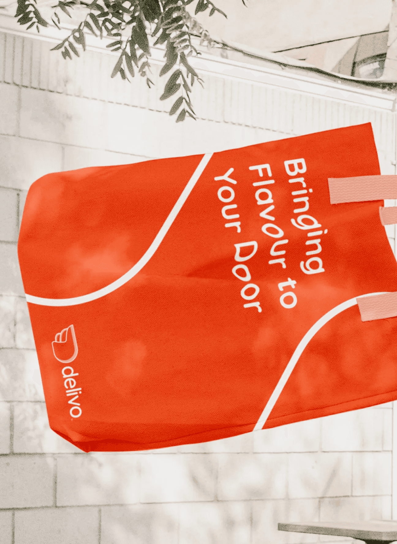 Red-orange delivery bag with white text 'Bringing Flavour to Your Door' and the brand name 'delivo