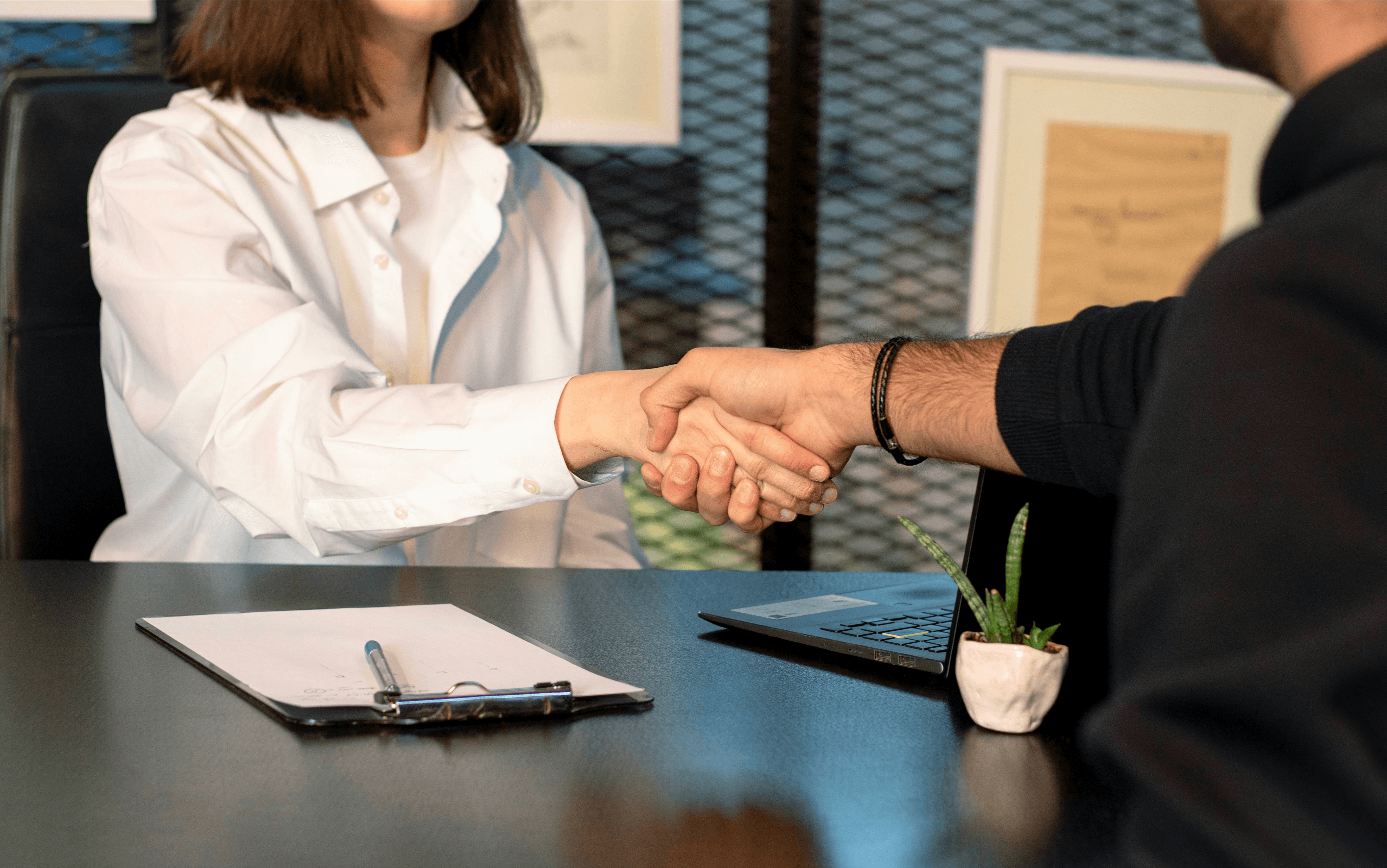 a man and a woman shaking hands in front of a laptop