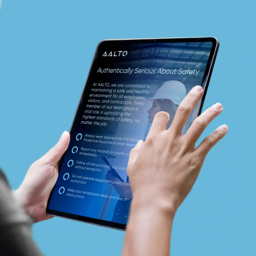 Hands holding tablet displaying AALTO safety guidelines with heading 'Authentically Serious About Safety' on light blue background