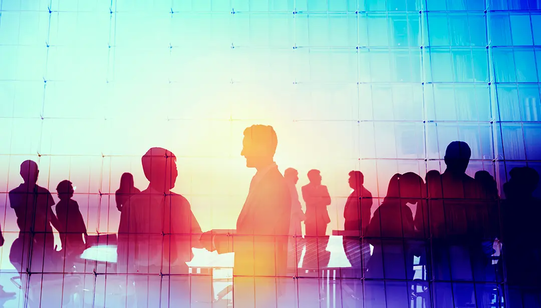 Silhouettes of business people shaking hands in a modern glass office building
