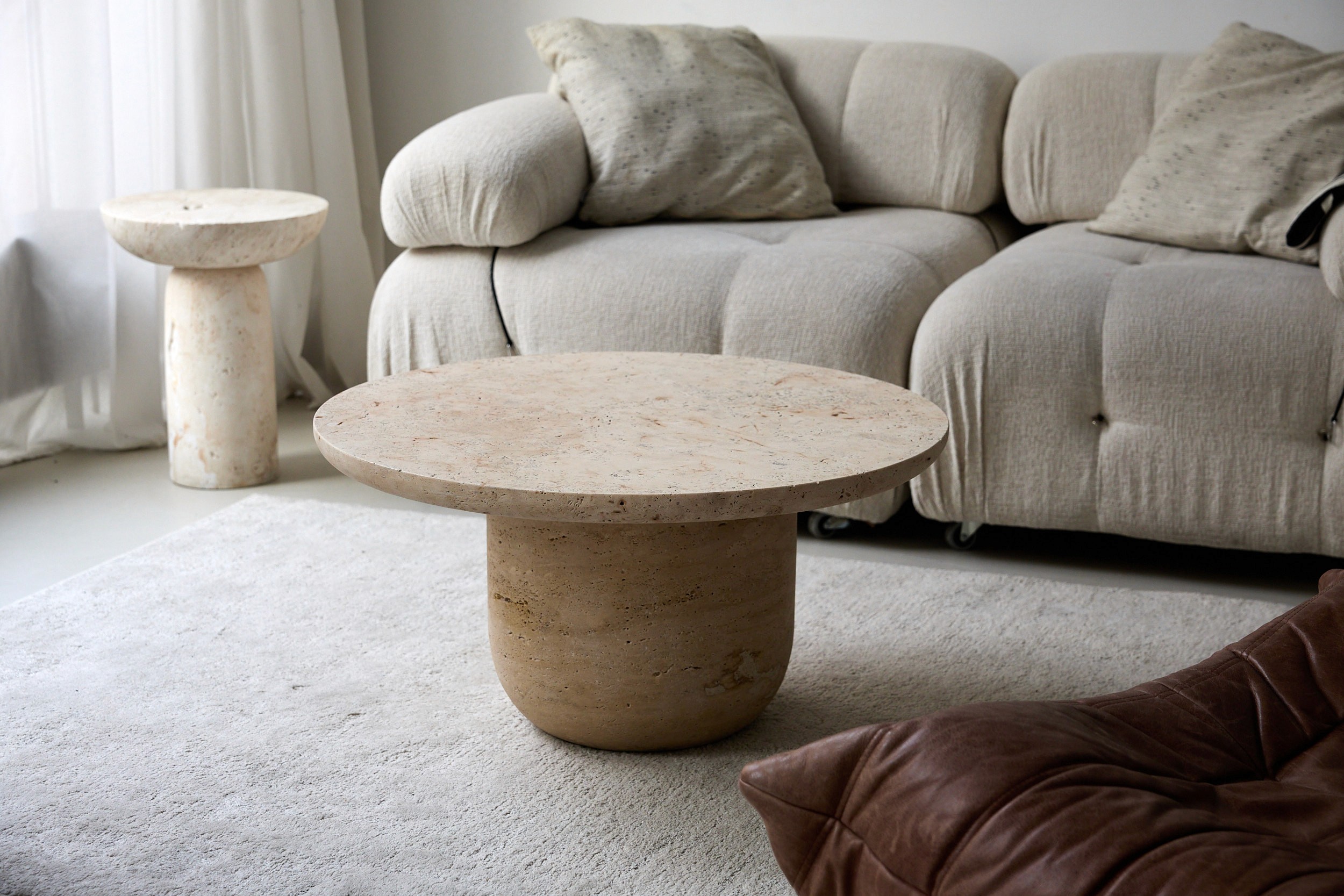 Runder Travertin Couchtisch aus Naturstein vor hellem Sofa