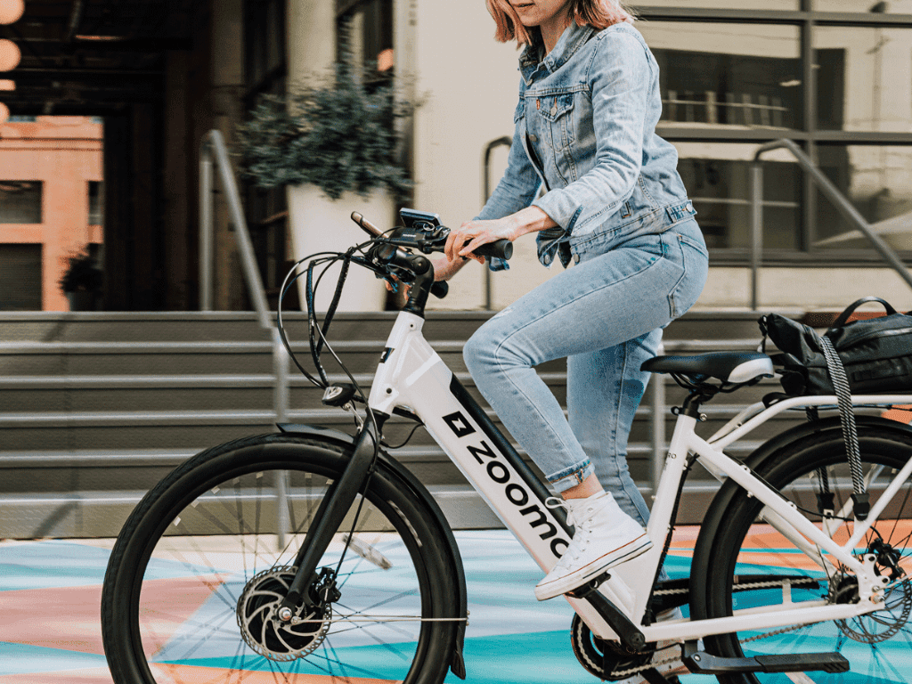 a lady in light denim pant and jacket riding a Zoomo bike