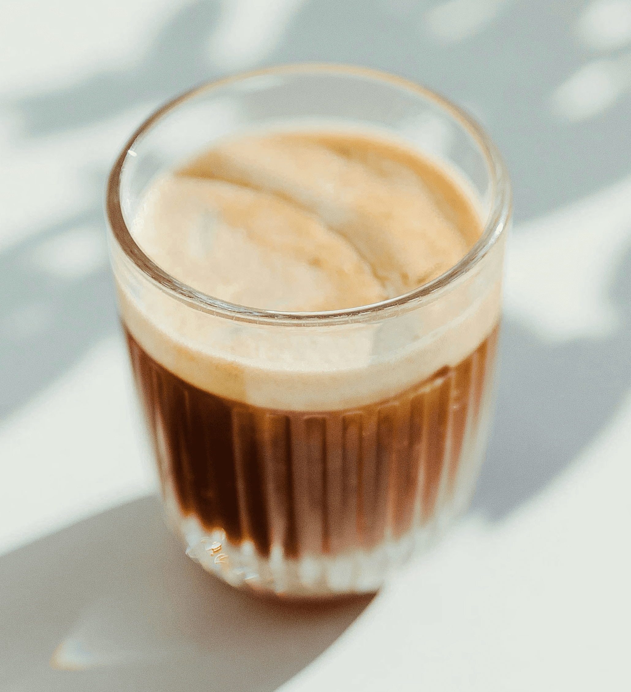 clear drinking glass with coffee on top of white table