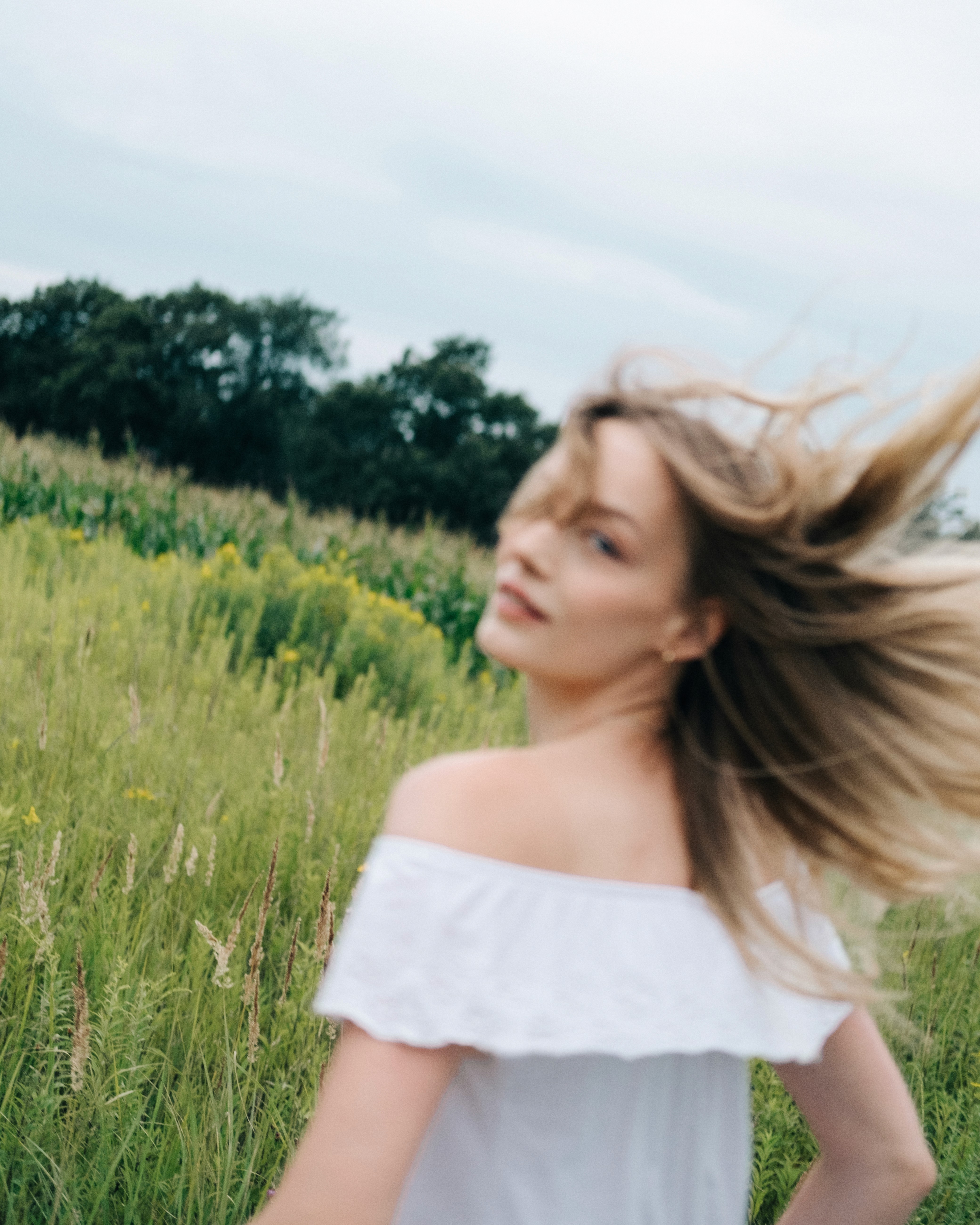 Hania – Cold Eden – motion-blurred moment turning back in a meadow, hair moving in the wind