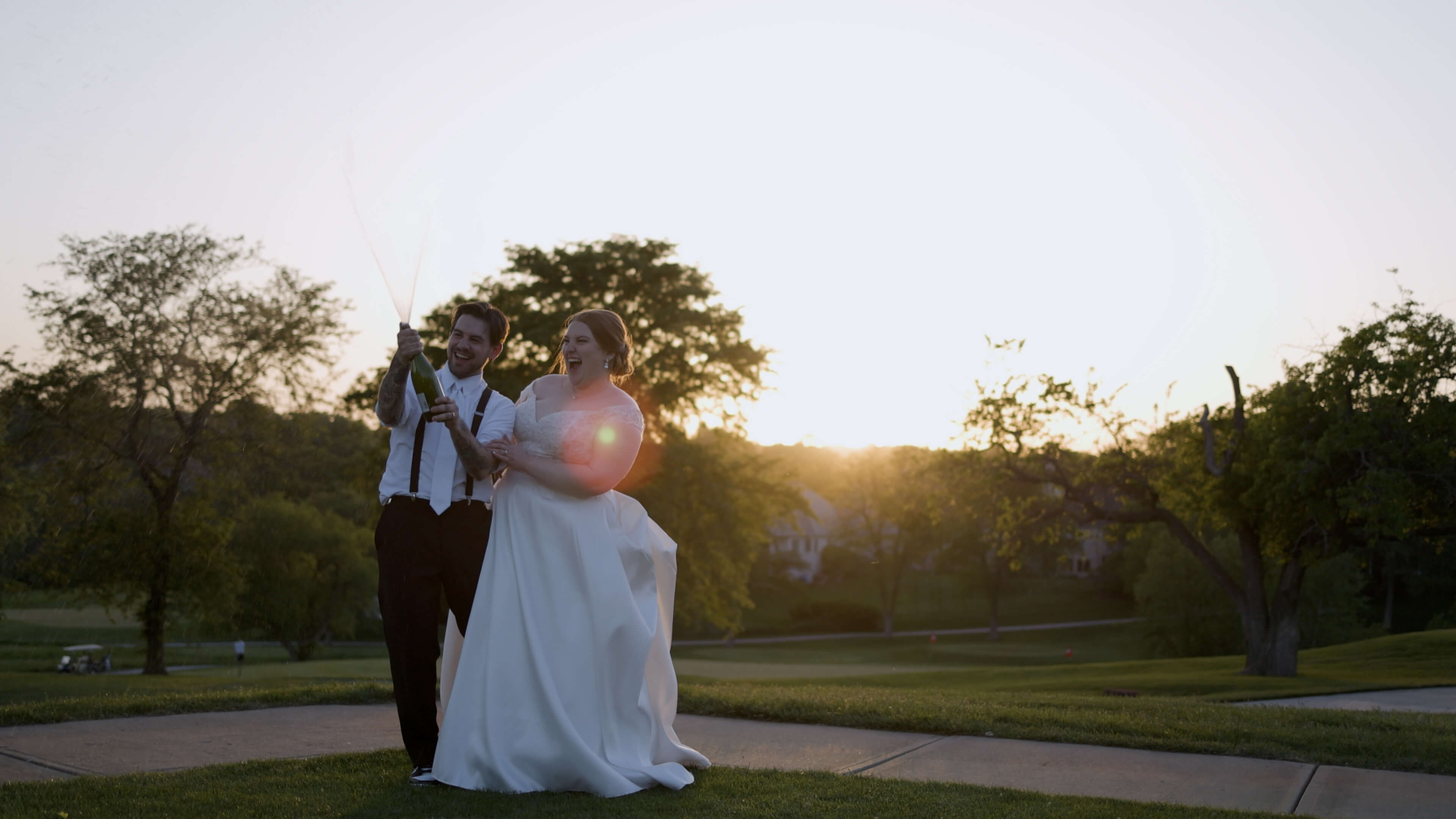 A bride and groom popping champagne at sunset