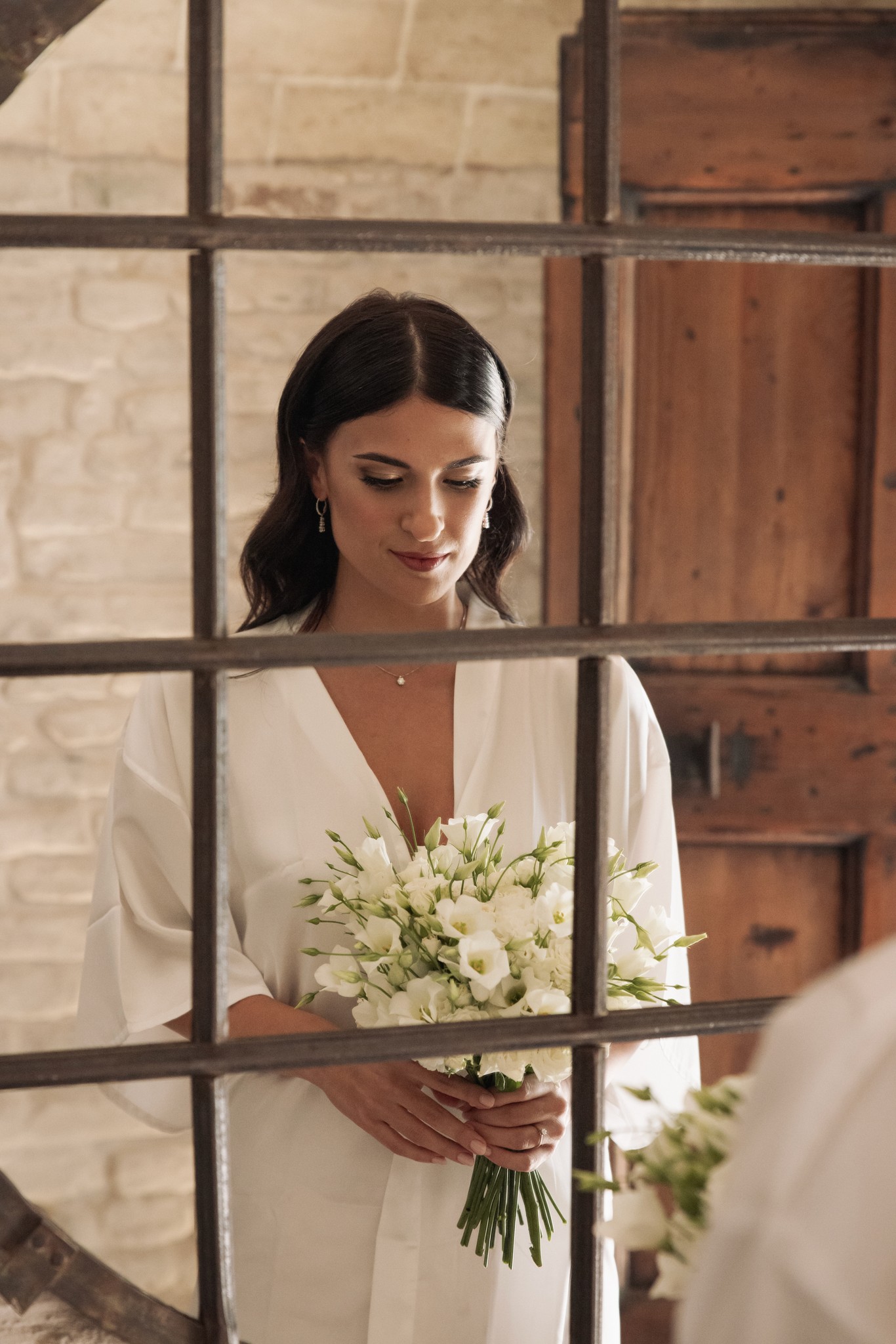Sposa in abito bianco con bouquet tra le porte di Villa Negri, sguardo sereno nei preparativi del matrimonio
