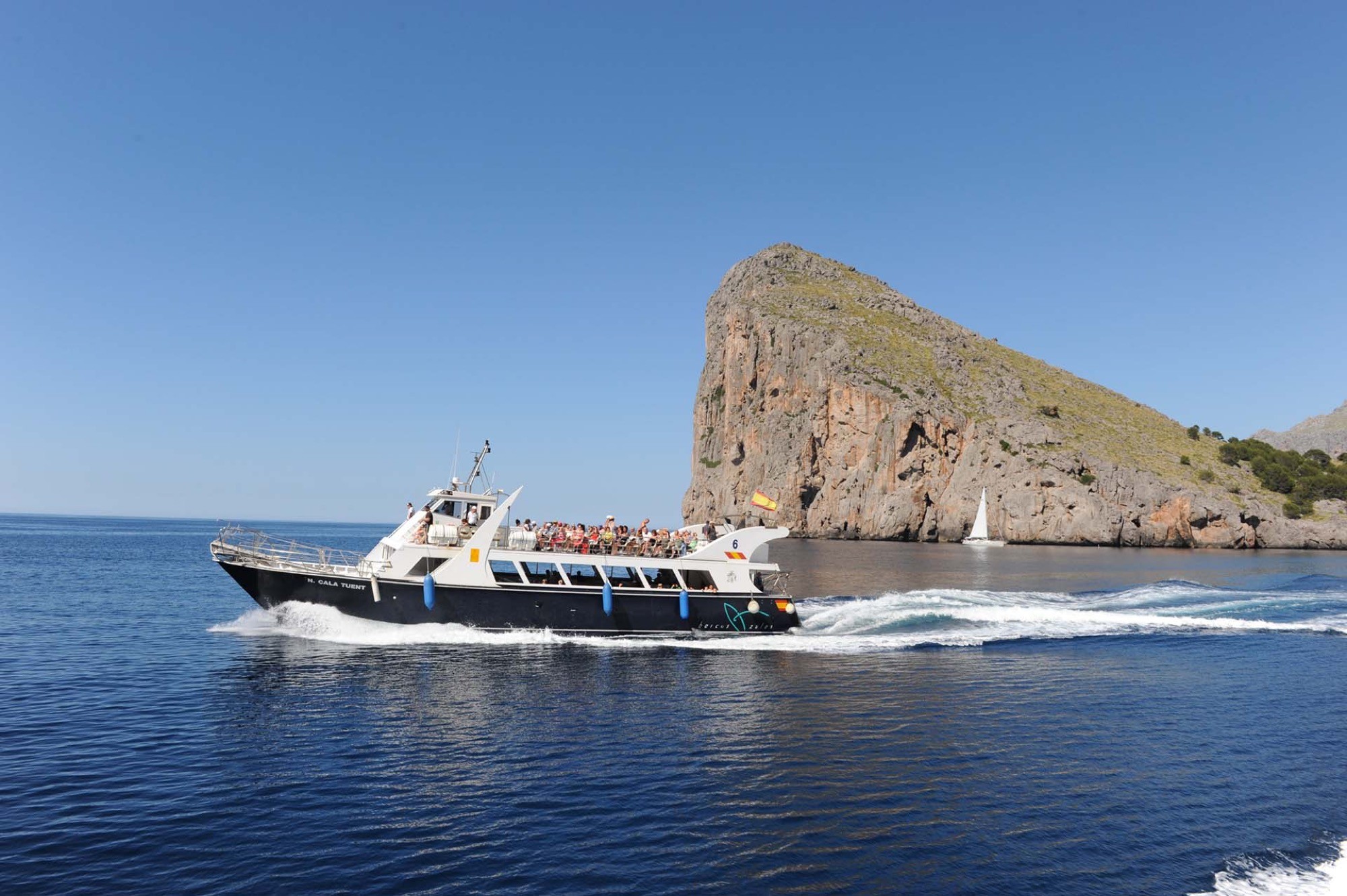 A boat sailing alongside the Tramuntana cliffs