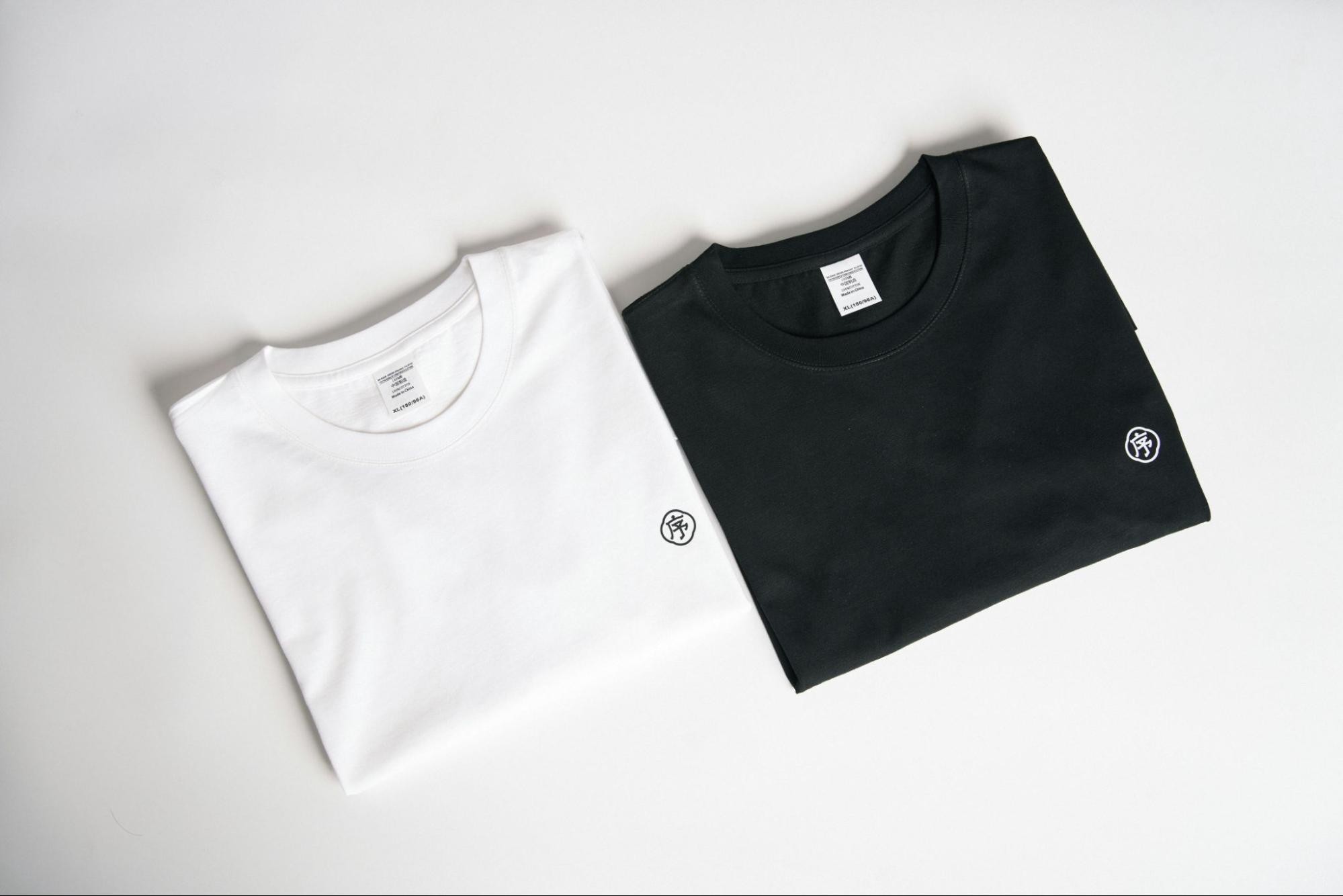 a pair of t shirts laid out, one black, another white