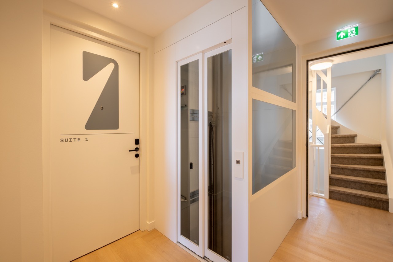 Entree van 1e Suite met lift, trapopgang en lichte gang in moderne afwerking