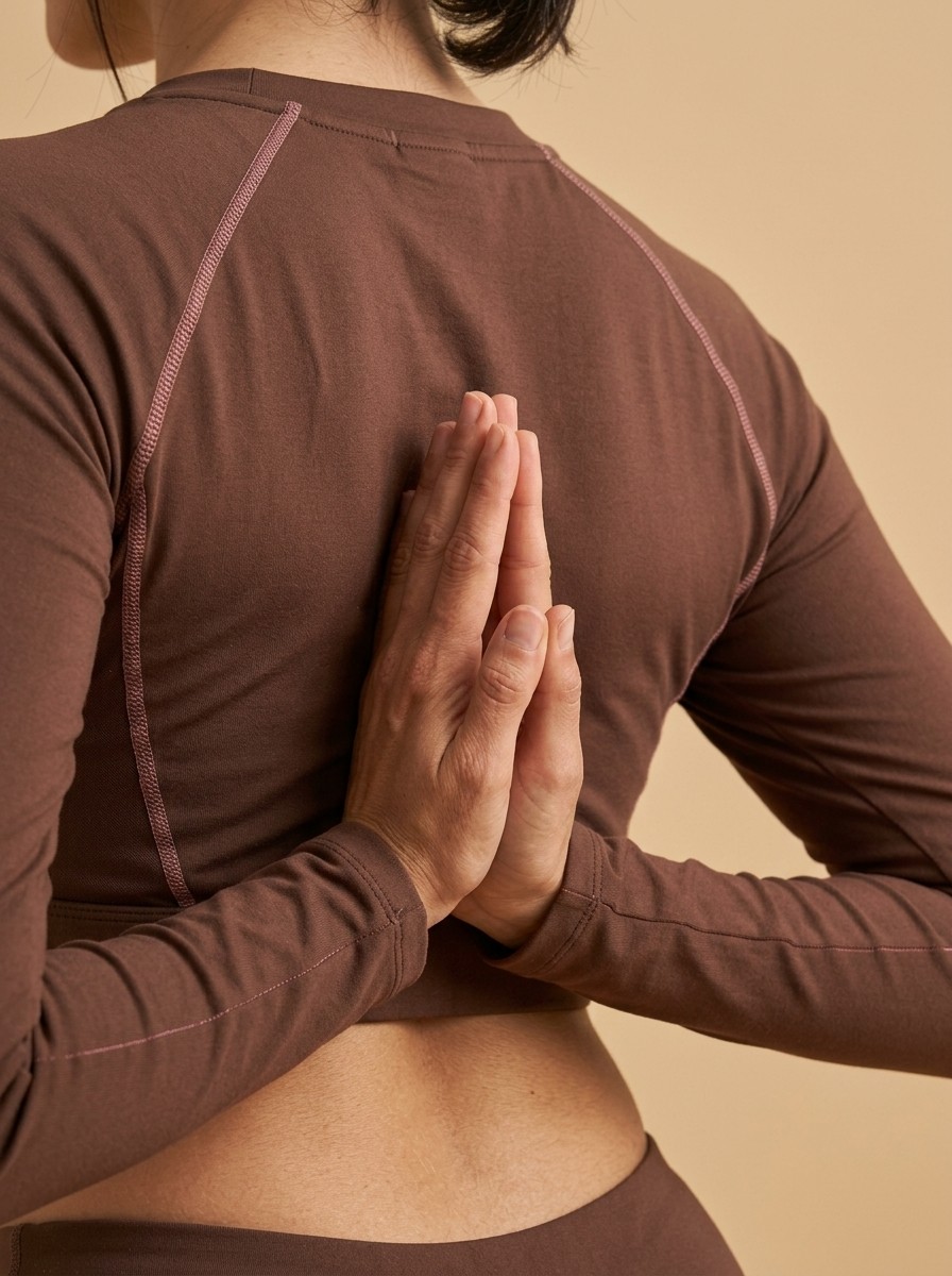 Close-up of a yoga practitioner's hands in a prayer position behind their back