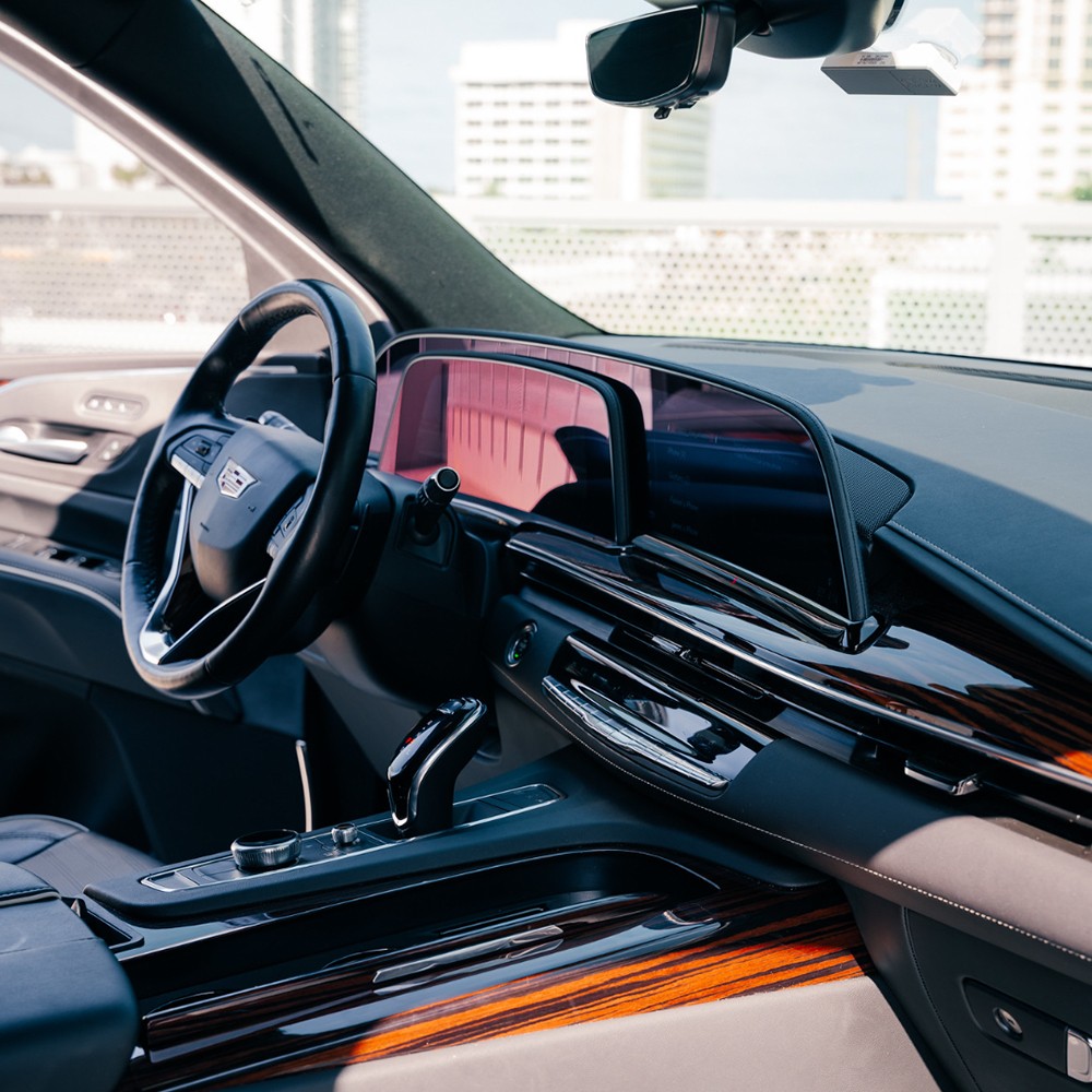 Cadillac Escalade interior showing full digital dashboard, wood accents, and premium trim