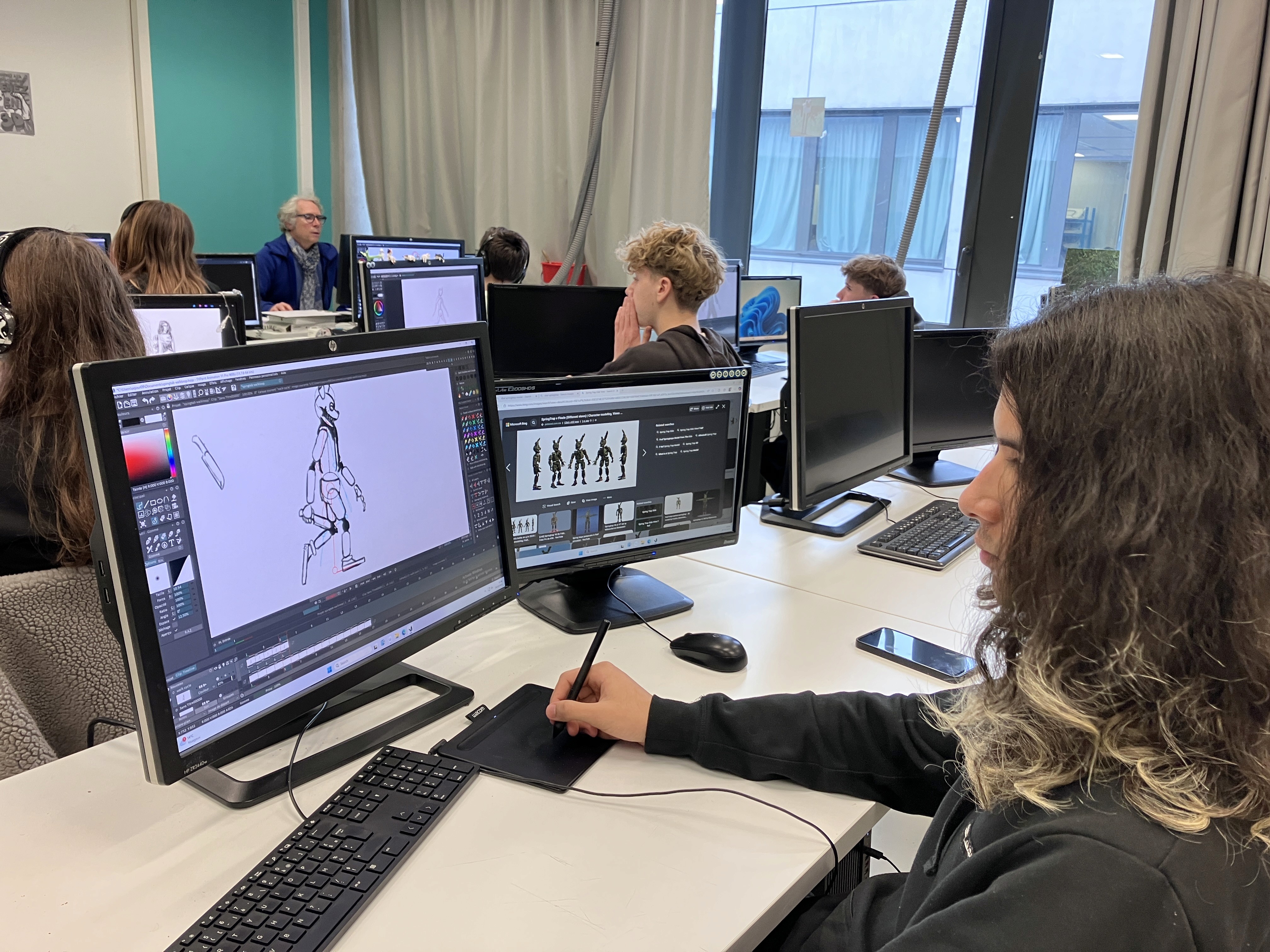 Femme concentrée travaillant sur un ordinateur, plusieurs écrans d'ordinateur sur son bureau.