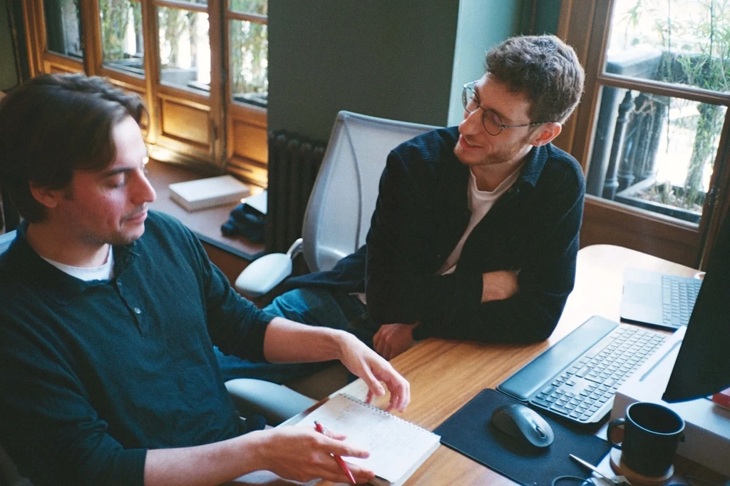 two employees working at a desk with a notepad and a computer