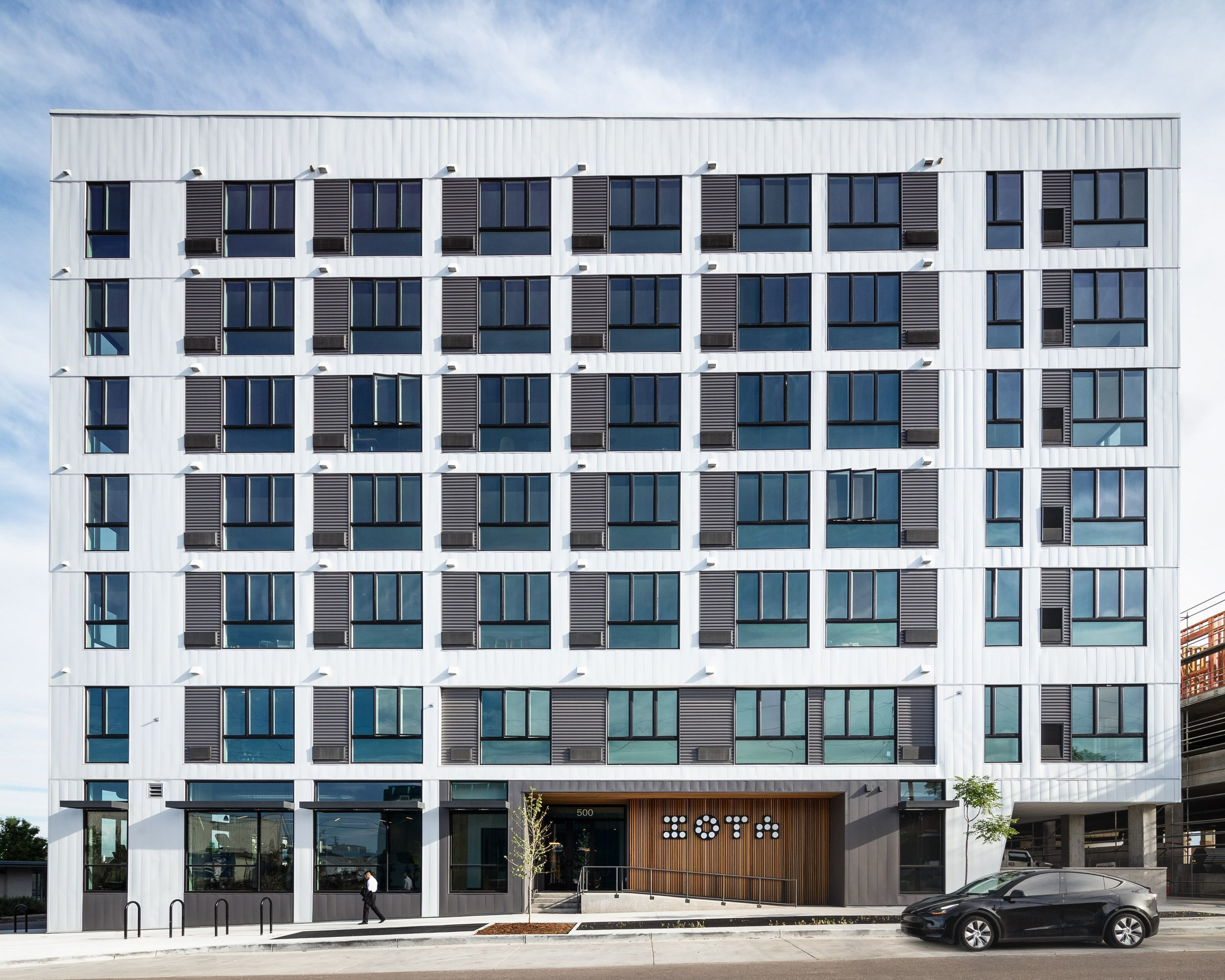 Modern white building with many windows and air conditioners.