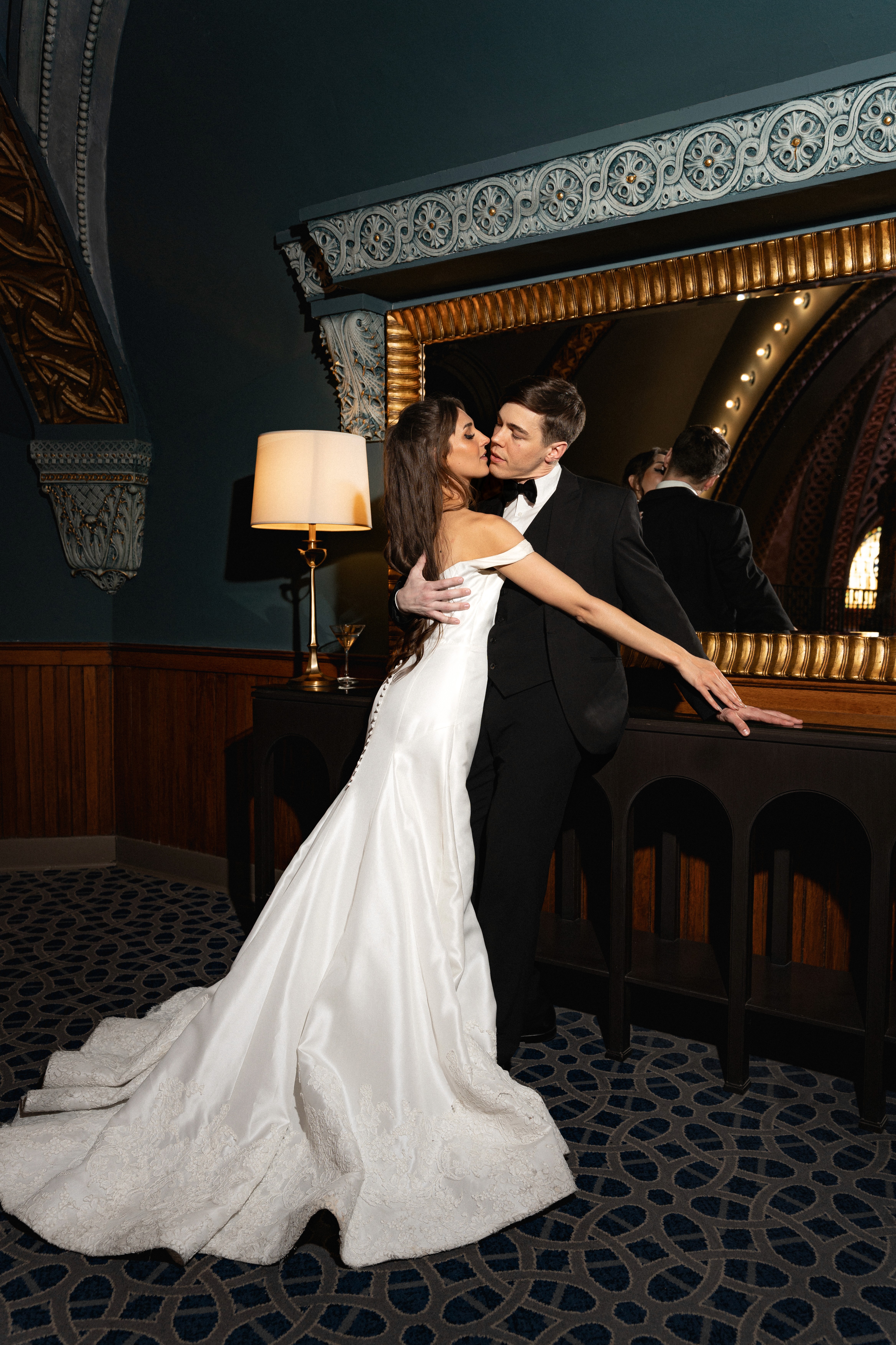 A bride and groom share a kiss surrounded by a joyful bridal party.