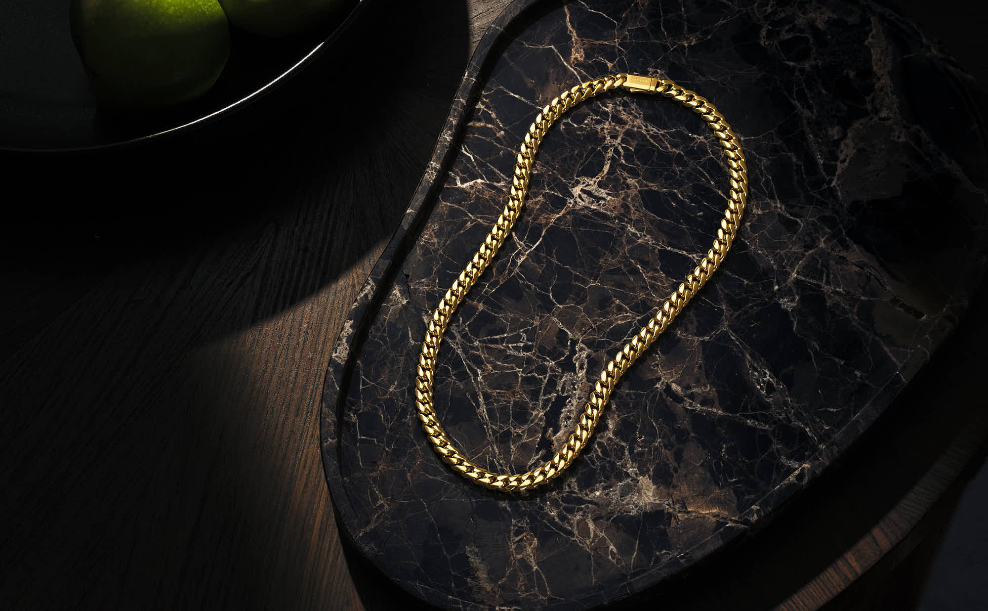 Elegant gold chain necklace on a marble surface.
