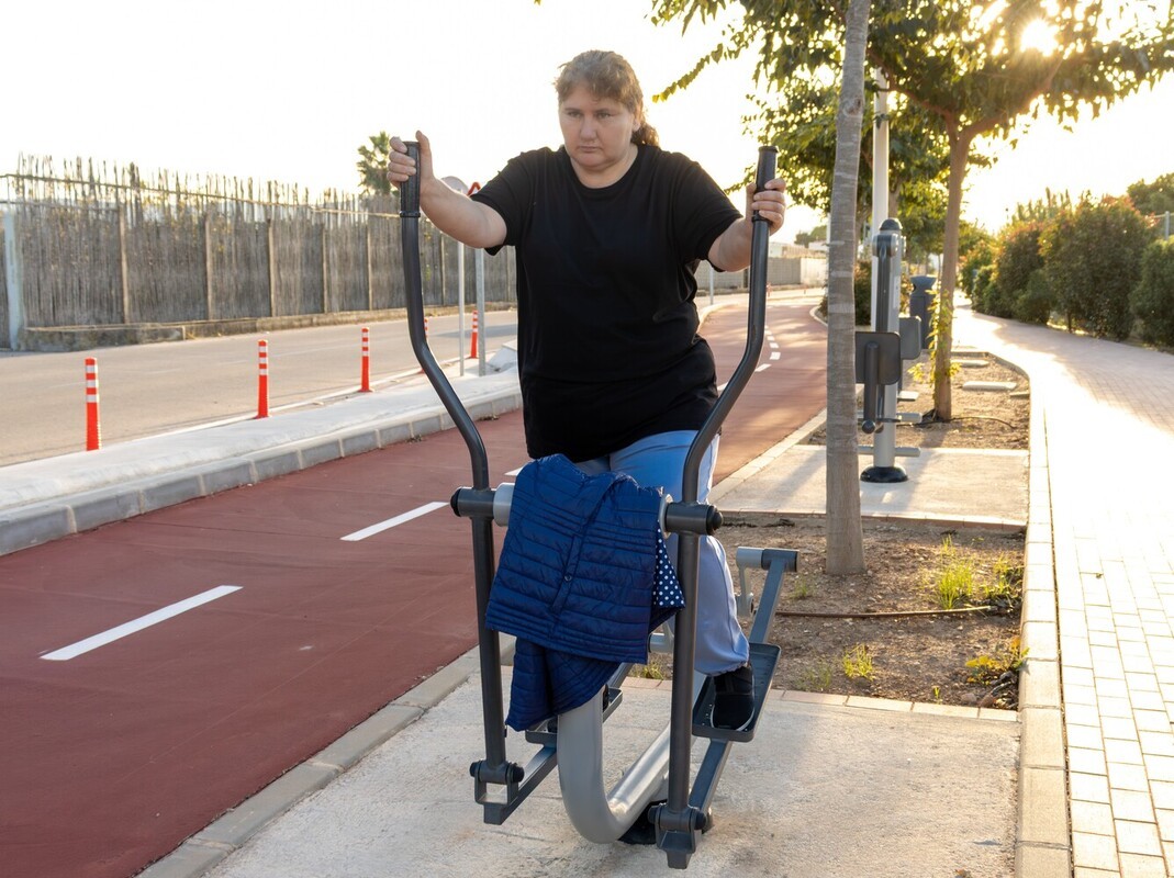 woman trying to achieve weight loss with walking and using an elliptical machine in an outdoor park