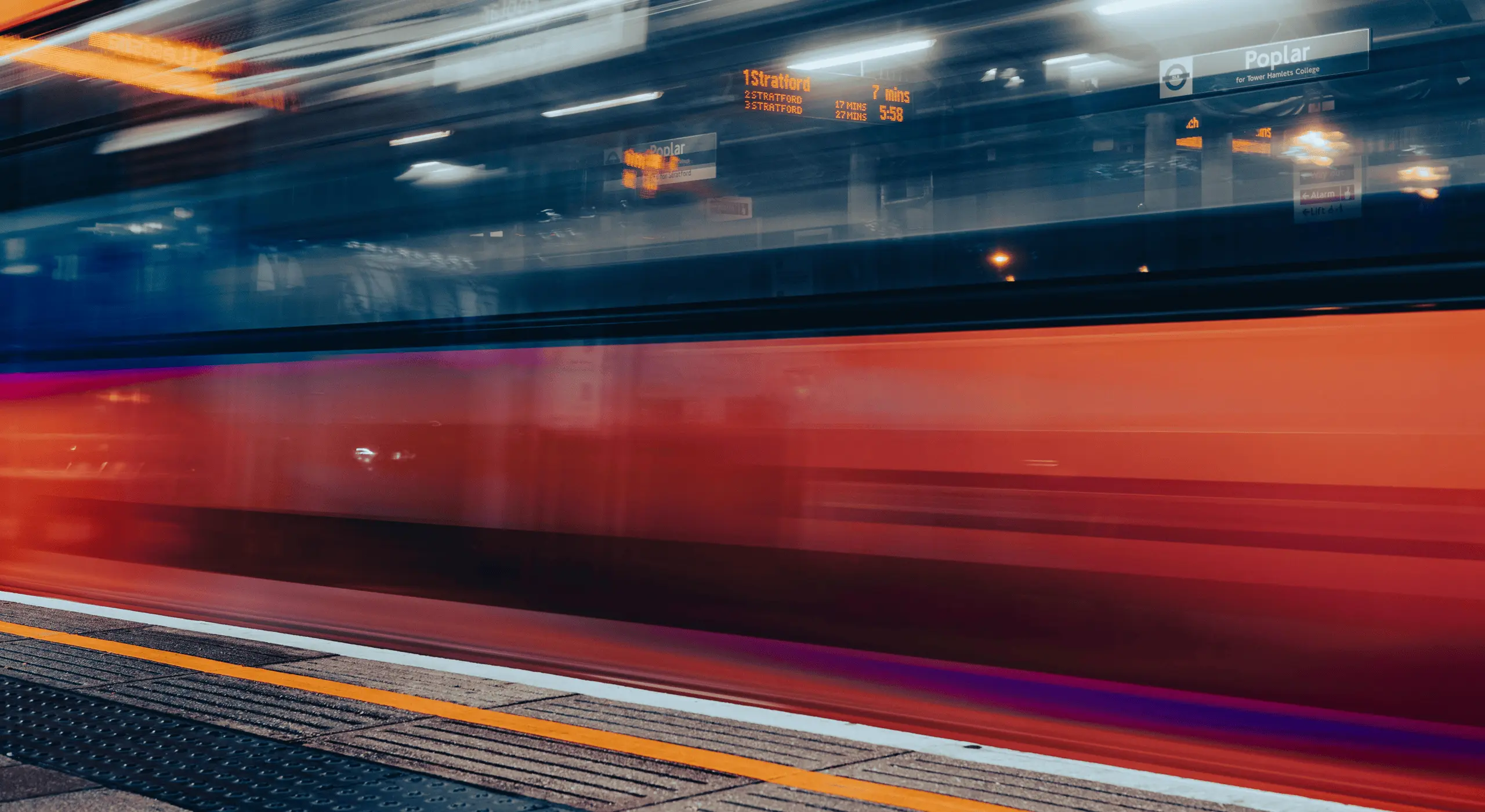 Blurred motion of a train speeding through a London station at night.