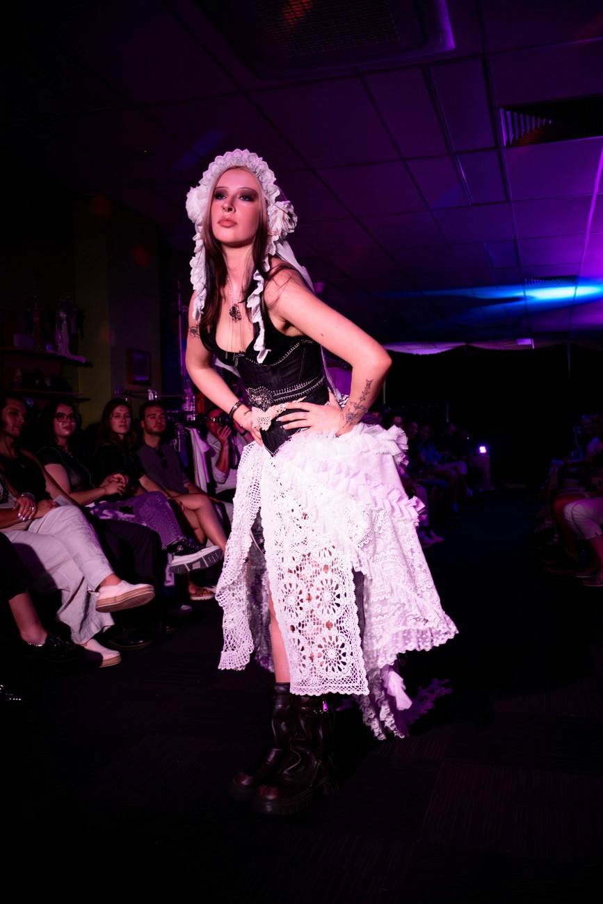 female model on runway wearing lace headpiece and skirt