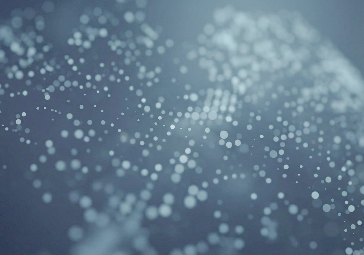 A talent recruiter with a soft smile working on her laptop in the office. The angle is on her face so we can't see what's is on the screen. She is wearing a blazer 