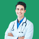 Smiling male doctor with dark hair, wearing a white coat and a blue shirt, with a stethoscope around his neck, standing against a black background.
