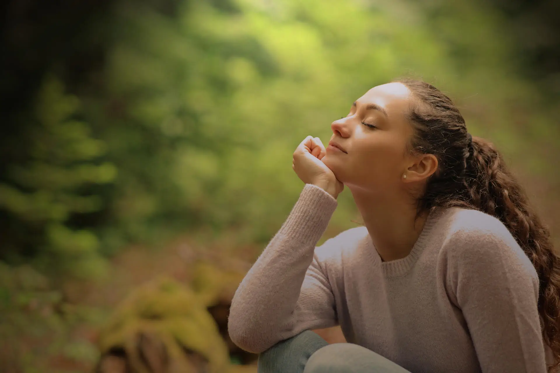 A woman in a forest, with soft natural light filtering through the trees.