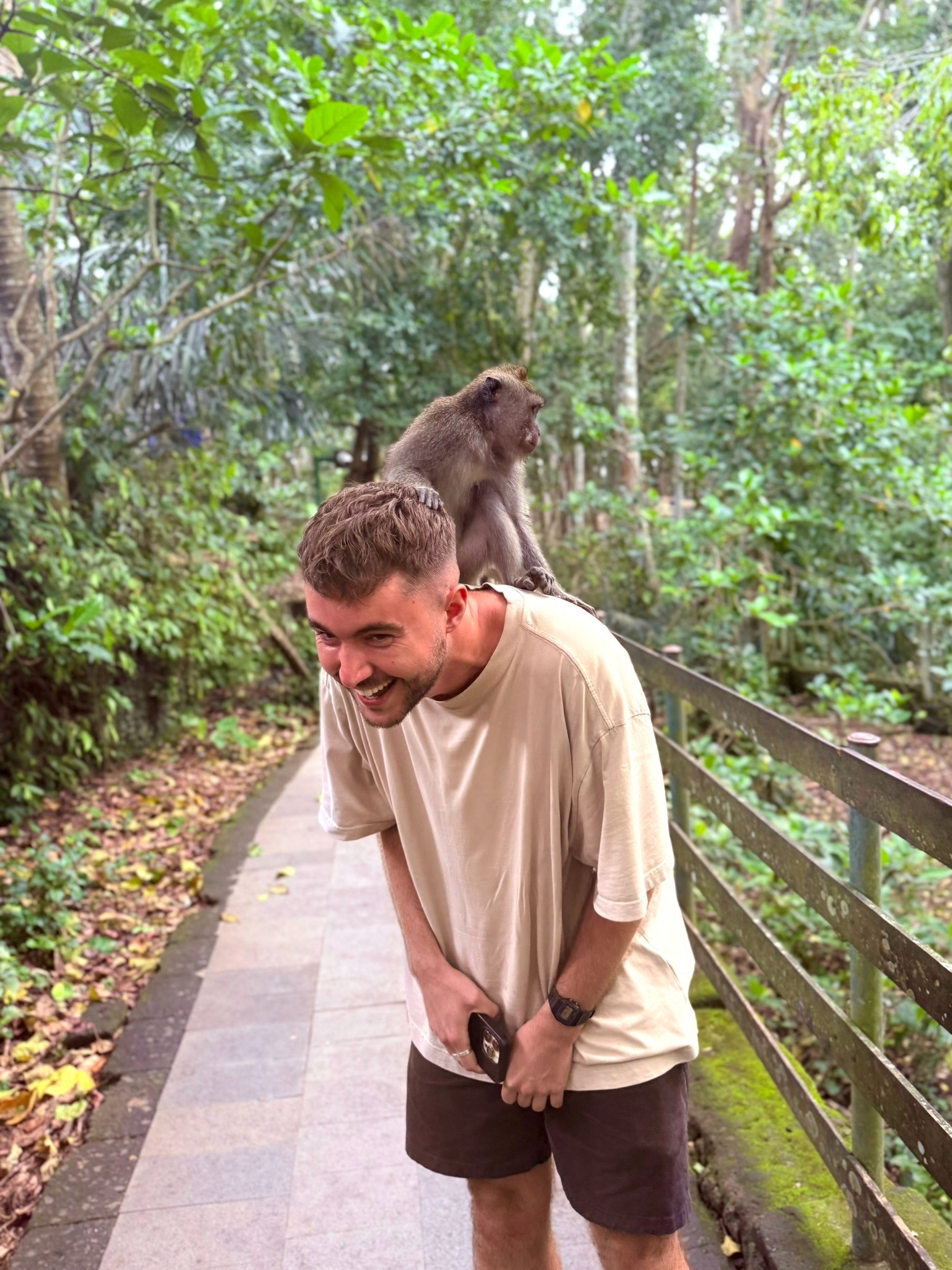 Person wearing a blue puffer jacket and red backpack standing in front of a light blue building on a city street.