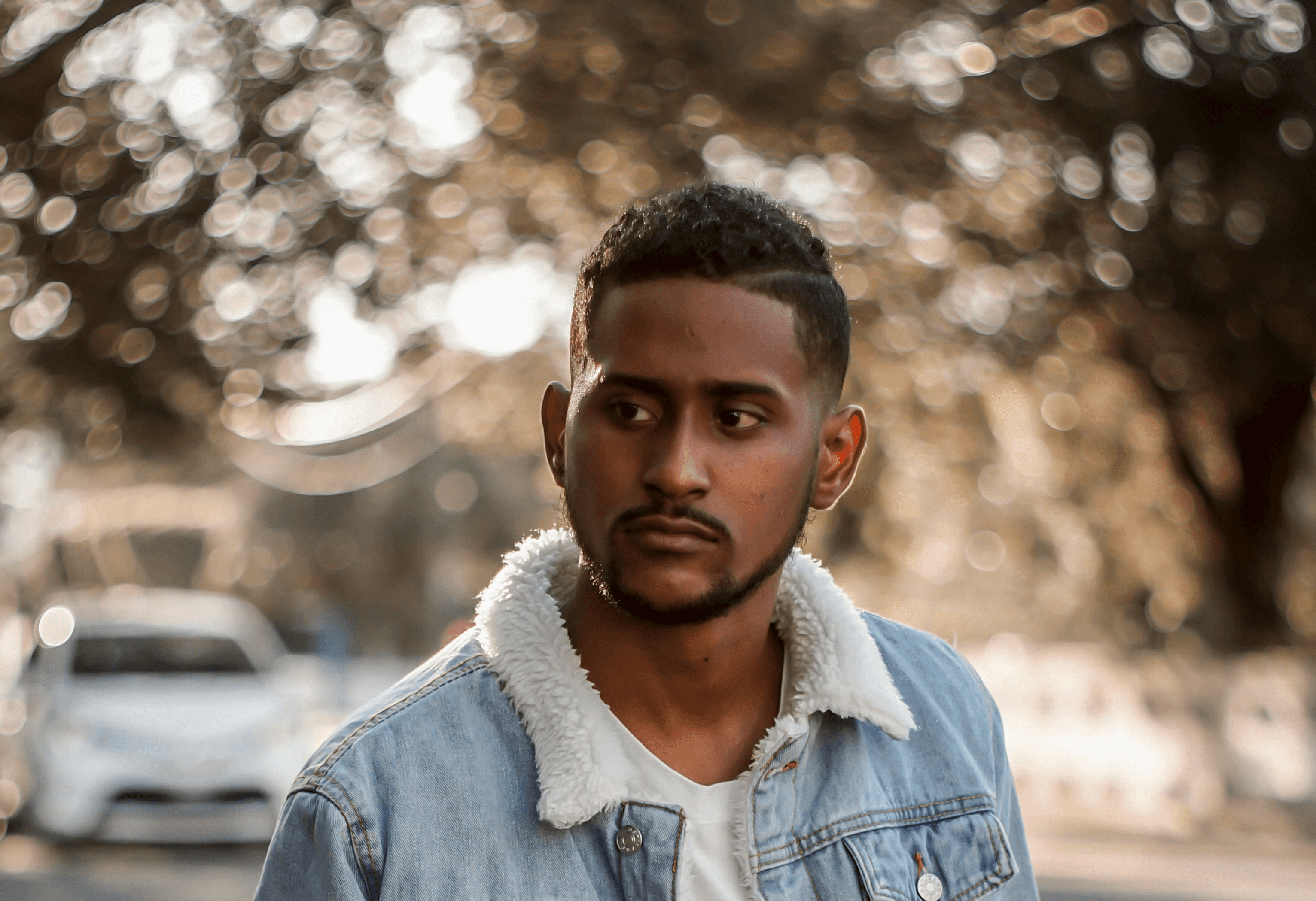 man in blue denim button up jacket standing on road during daytime