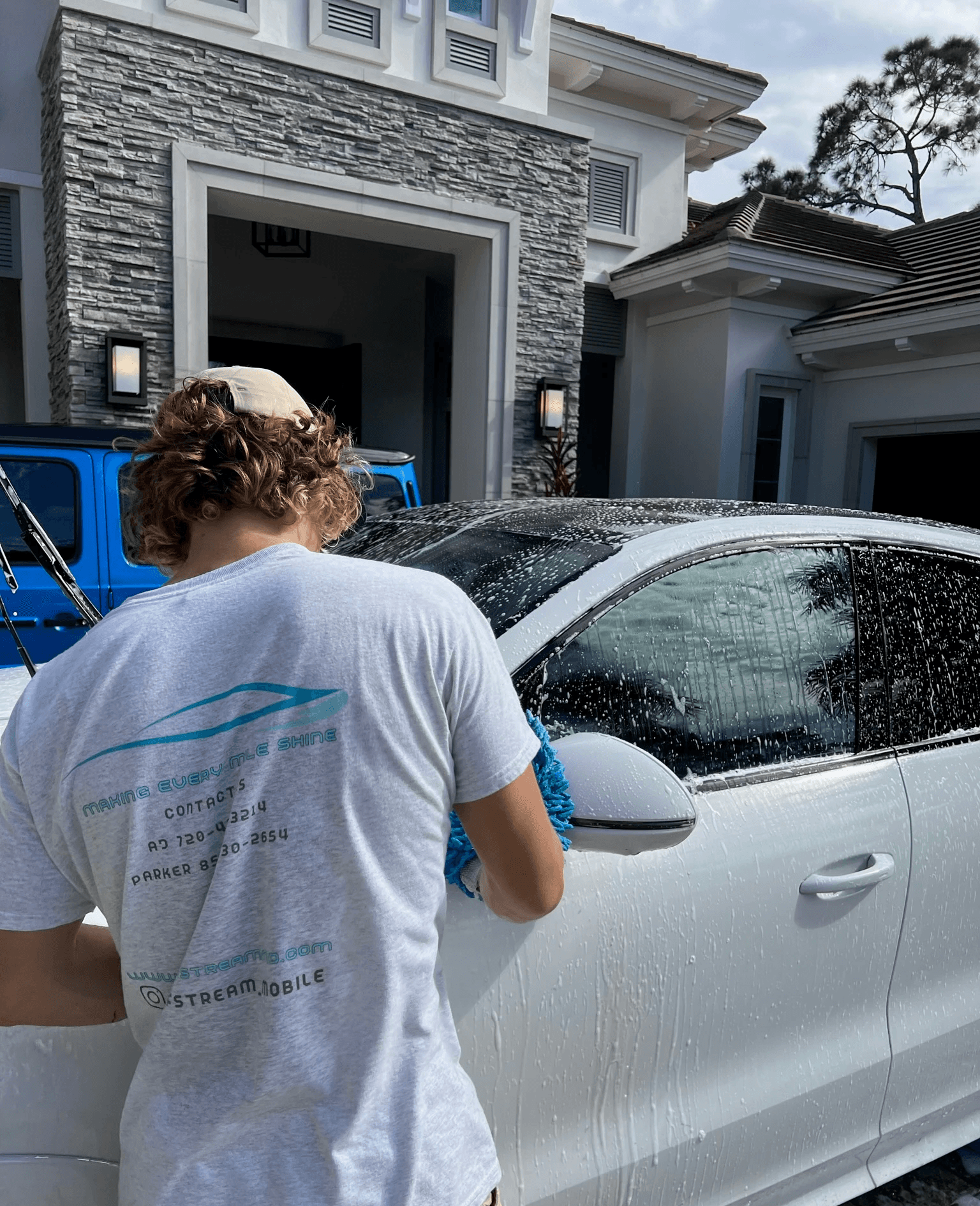 Owner of gulfstream mobile detailing hand washing a white porsche cayenne 