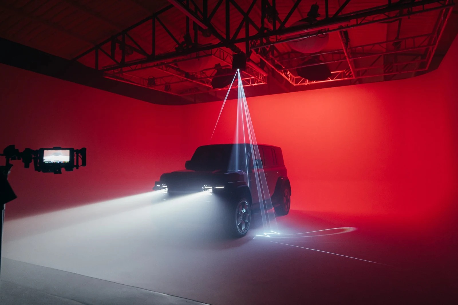 Laser beams and headlights cutting through haze around the Chery V23 against a red cyclorama
