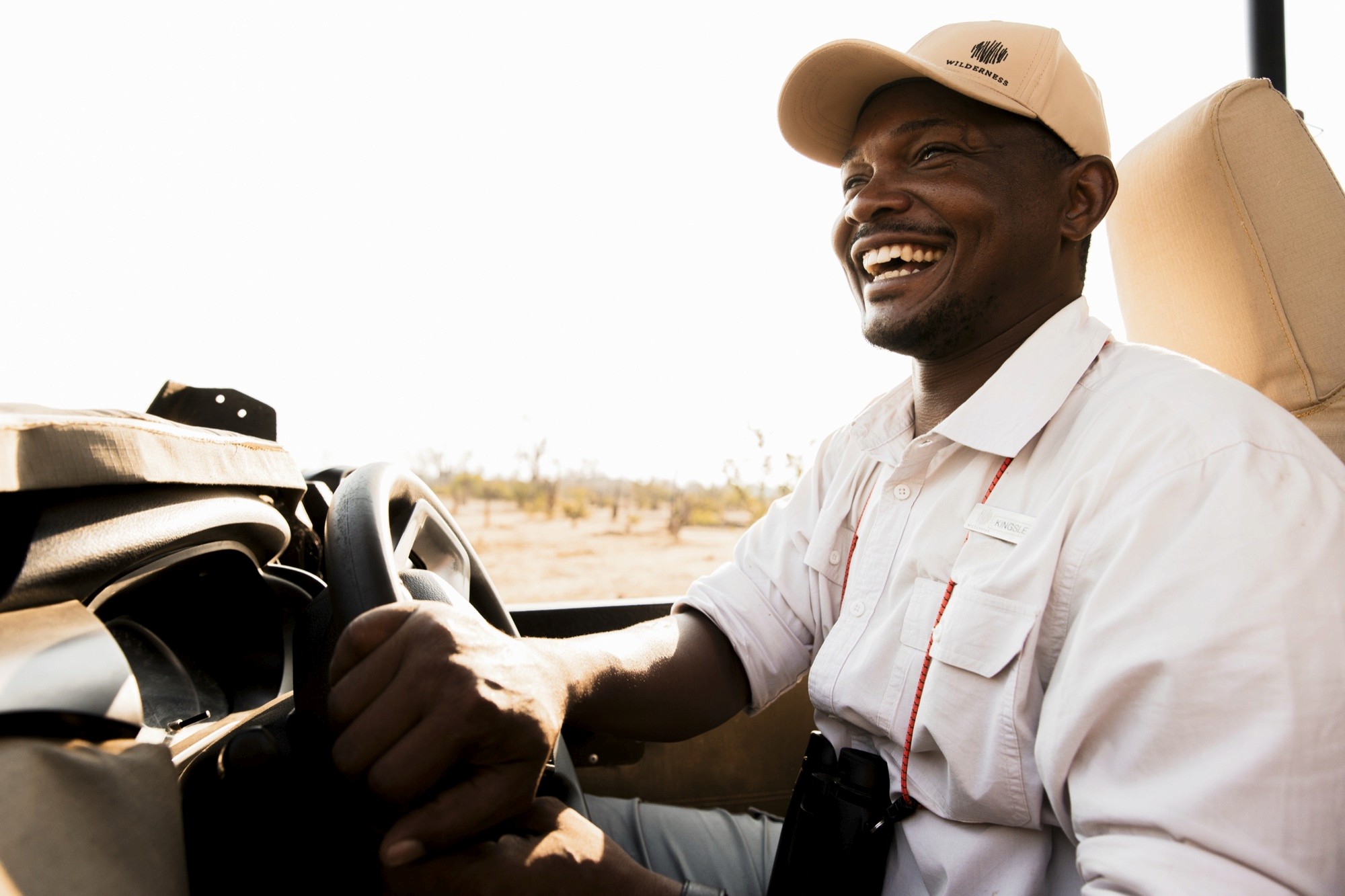 A guide's easy smile at the wheel of an open safari vehicle