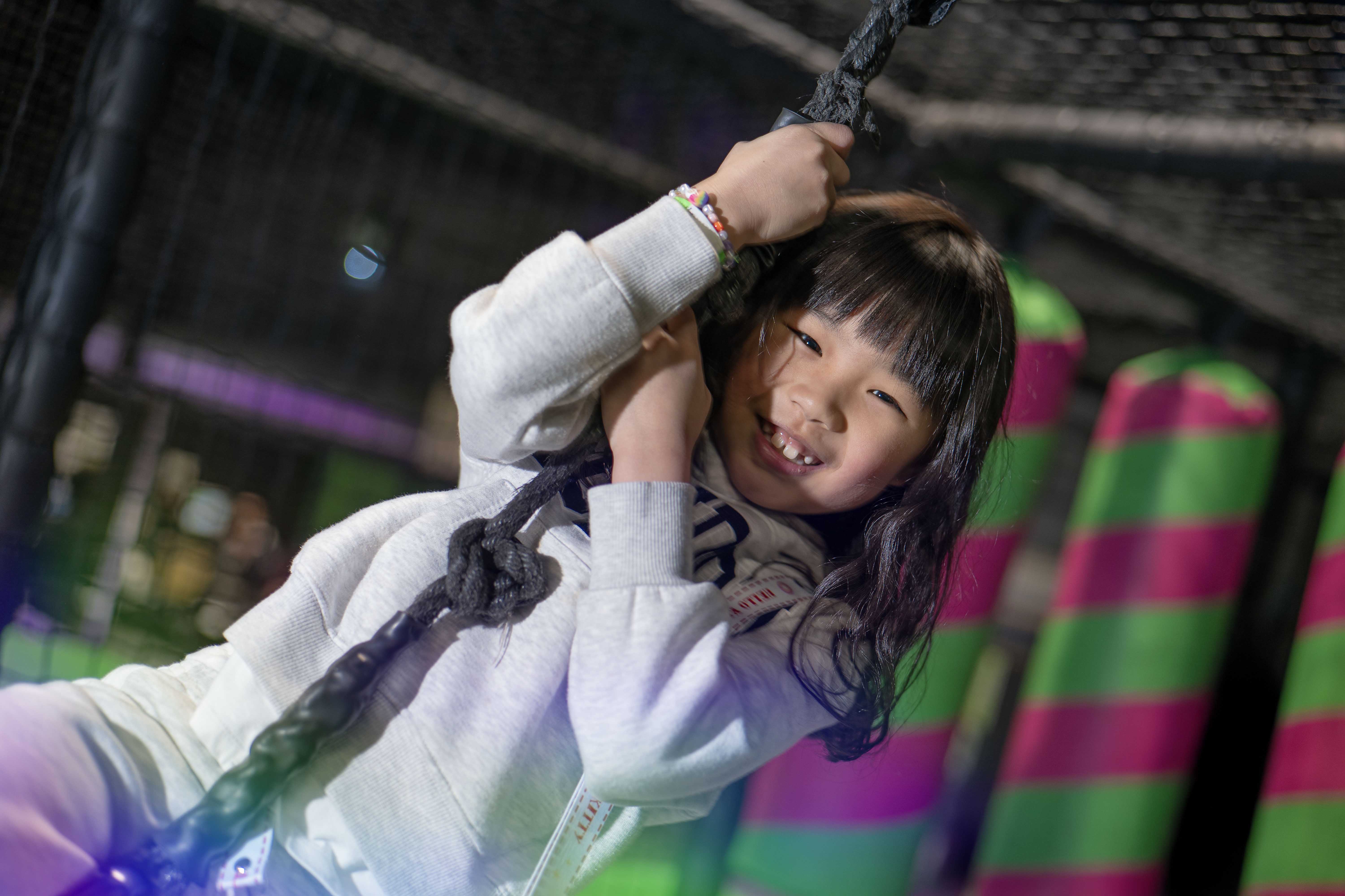 young girl hanging onto bright coloured play area at Flip Out adventure park