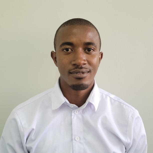 man in white polo shirt and black pants standing beside white wall during daytime