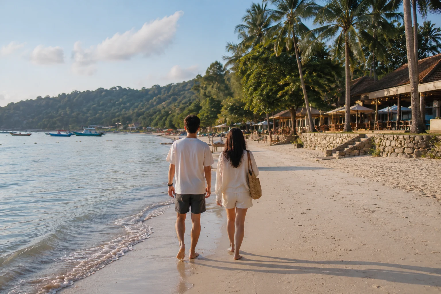 Couple walking together on a peaceful sandy beach beside the ocean.