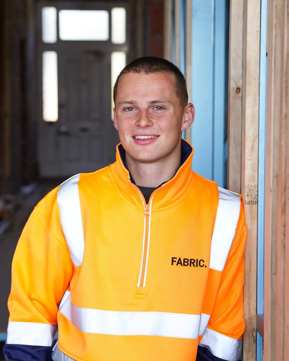 Construction worker in high-visibility safety gear standing in a building under renovation.