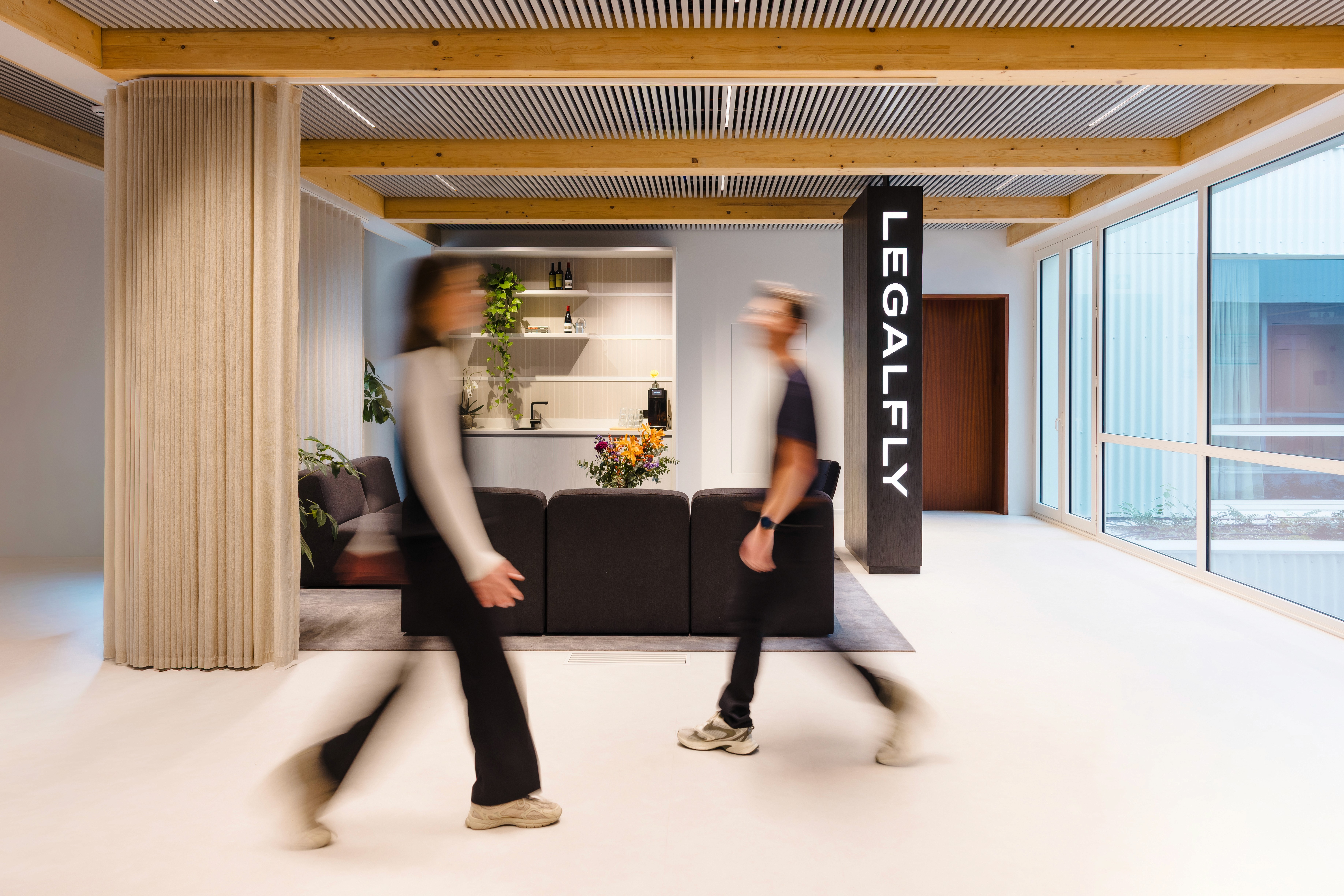 Black and white image of people working at a table with laptops, showing hands gesturing during discussion of digital content displayed on screens, with fabrica® logo in the corner.