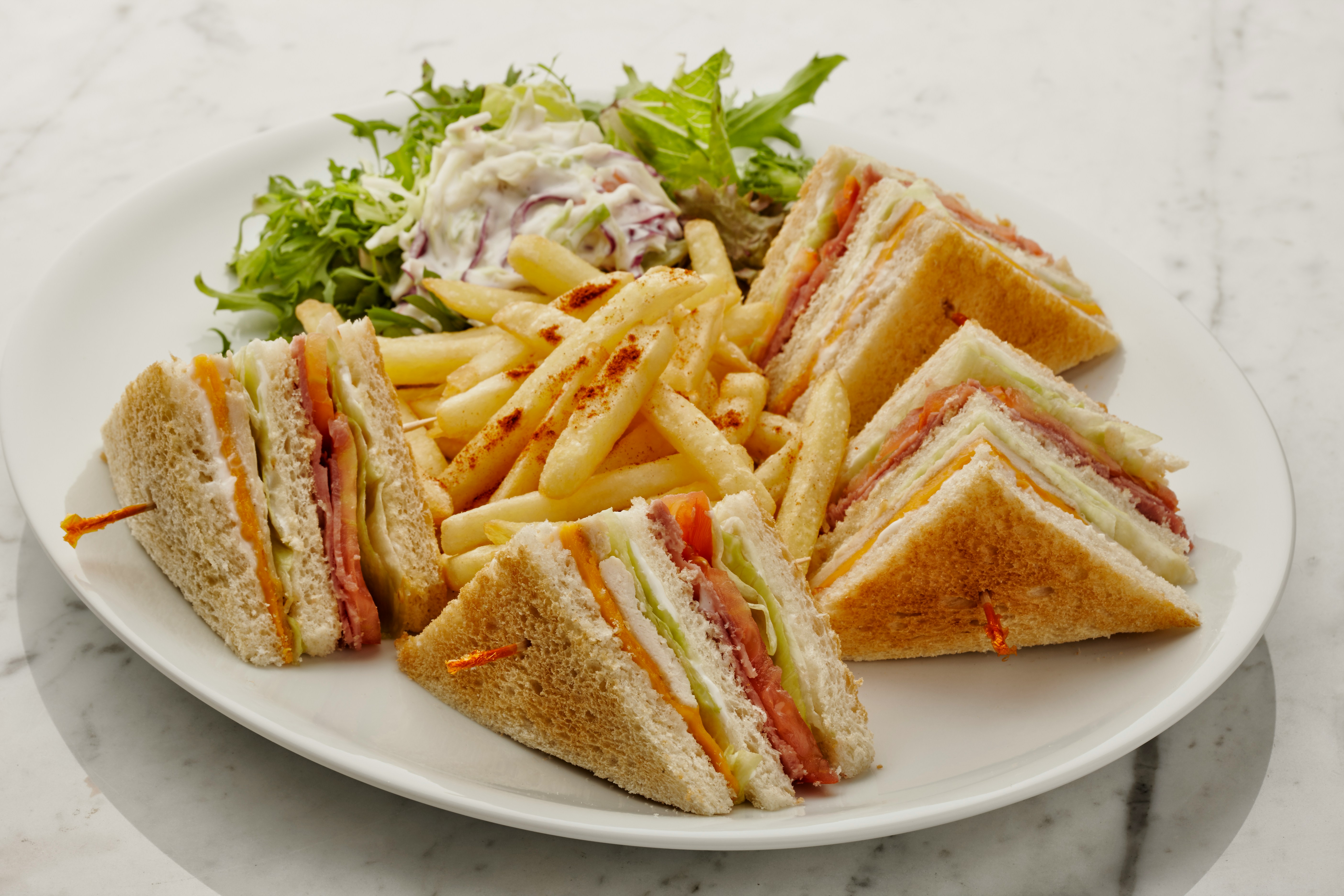 a white plate topped with a cut in half sandwich and fries