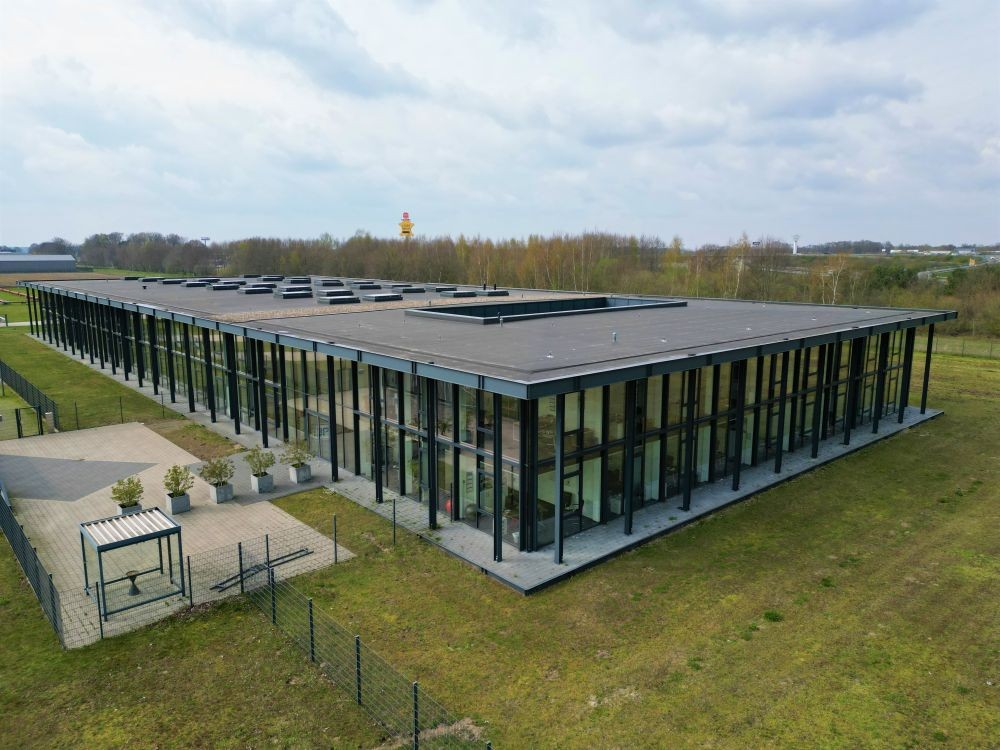 Modern, rectangular office building of 3P Services headquarter with large windows and a flat roof, surrounded by green grass.