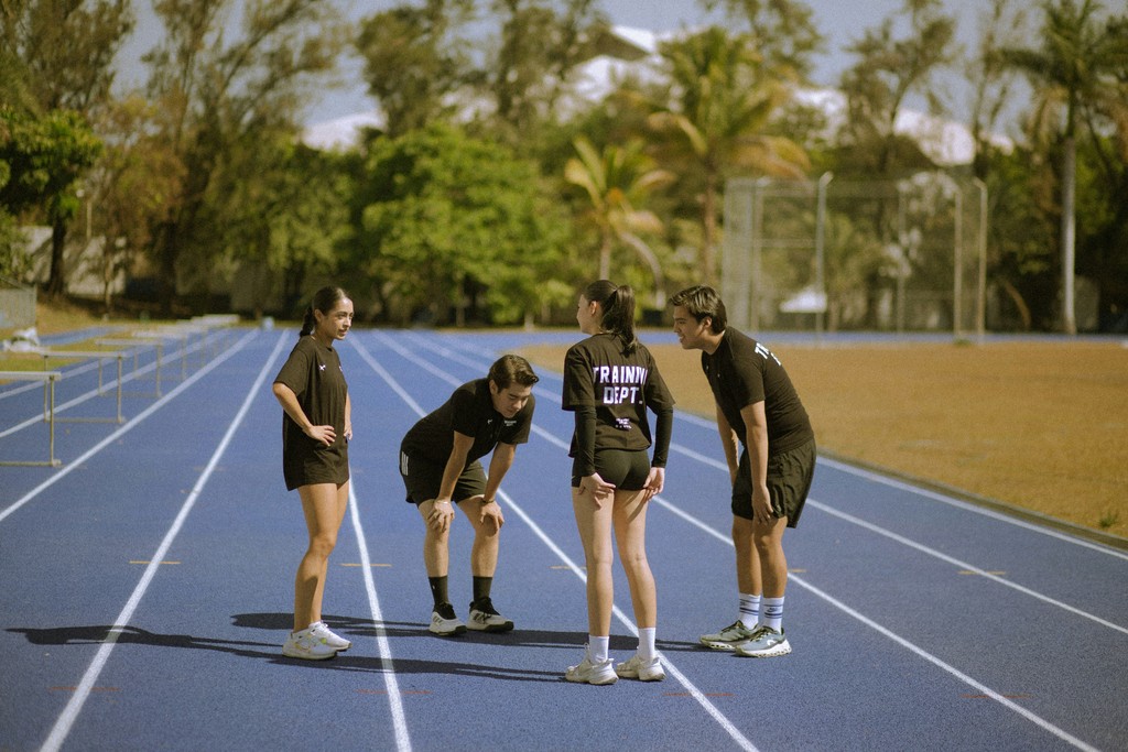 Four athletes in black on a blue running track