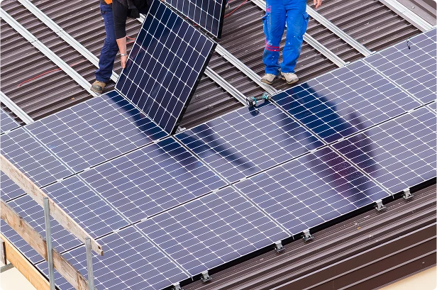 Solar panel repair crew fitting panels on metal roof
