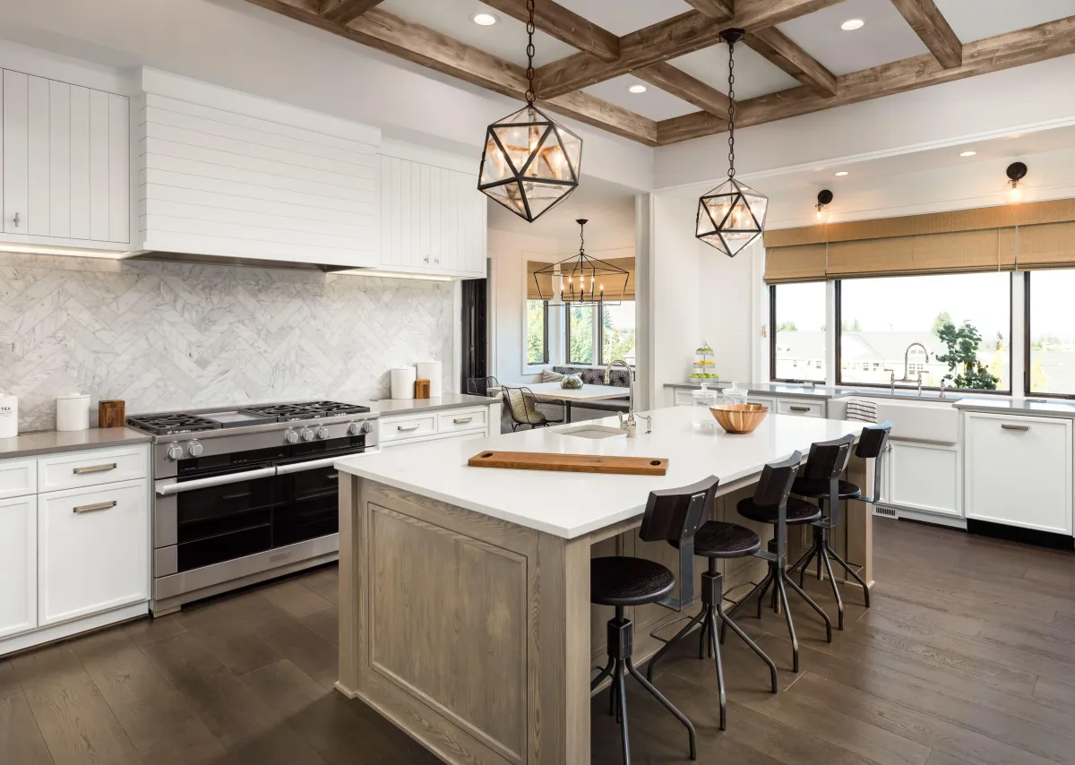 Transitional kitchen renovation by B&Y Reno Corp with a large center island, marble backsplash, farmhouse-style lighting, and natural wood ceiling beams.