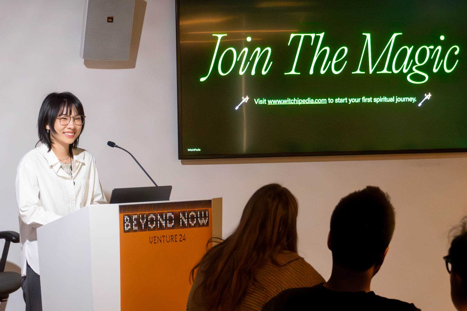 A lady at the podium giving a presentation to a class.