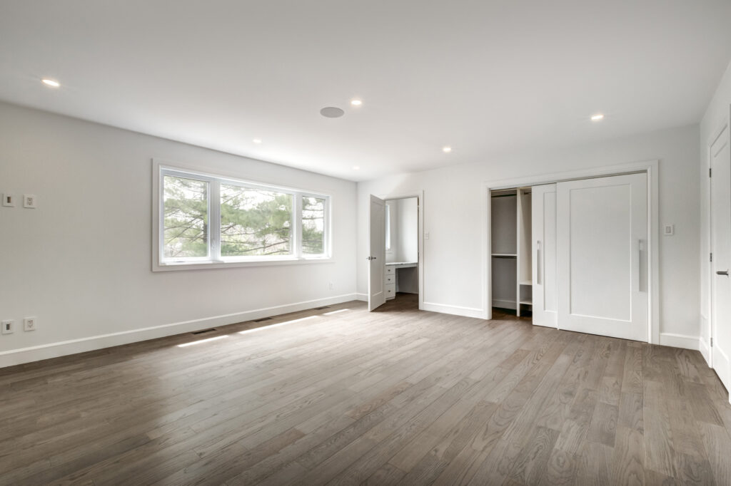 Bright open-concept kitchen and dining area with black and white marble waterfall island, sleek white cabinetry, and glass staircase, showcasing B&Y Reno Corp’s custom kitchen remodeling in a modern luxury home.