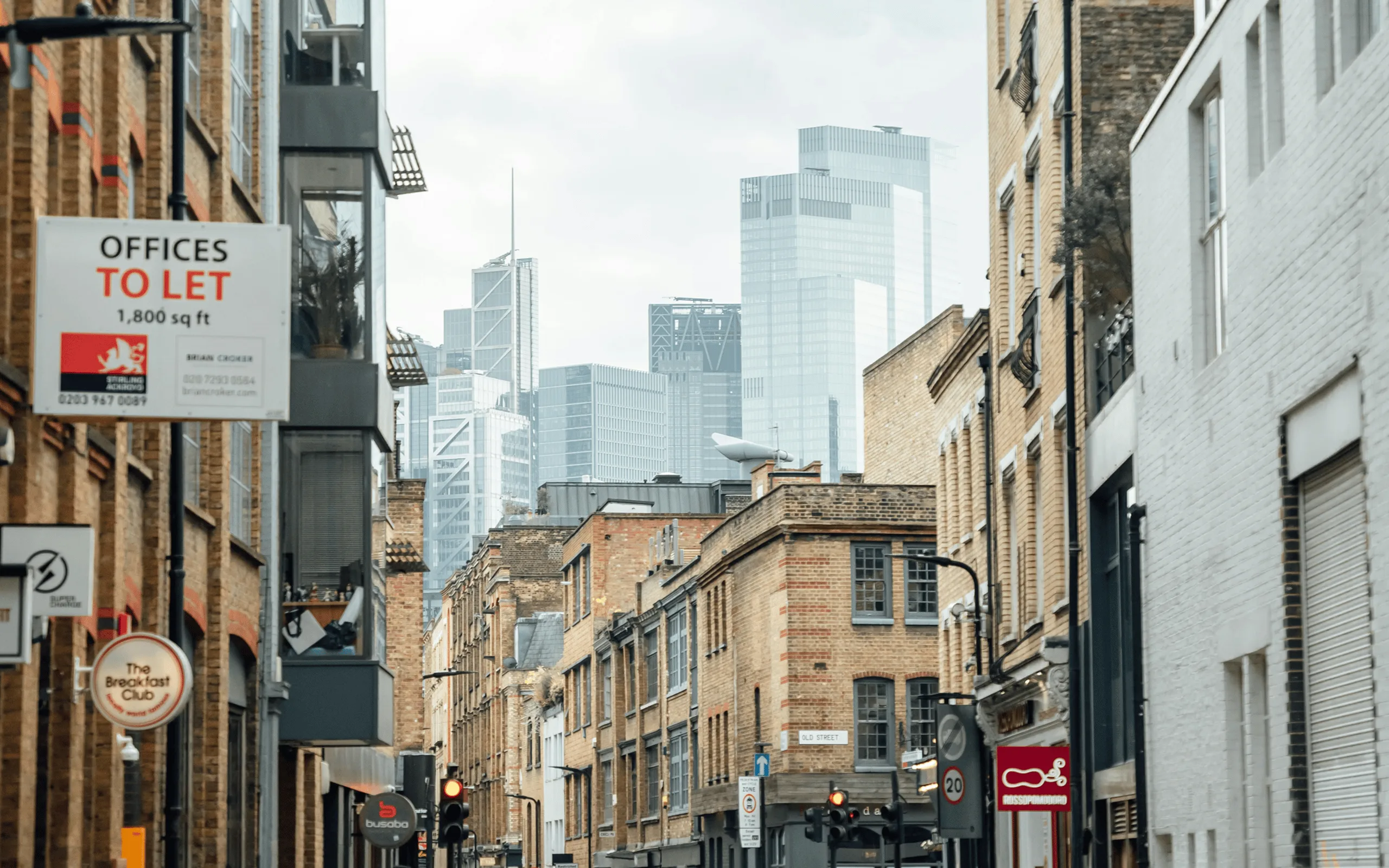 London street with an “Offices To Let” sign and modern buildings.