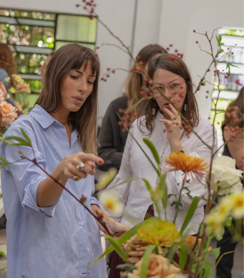 Taller de diseño floral con enfoque colaborativo, mujeres observando y creando arreglos con flores silvestres.